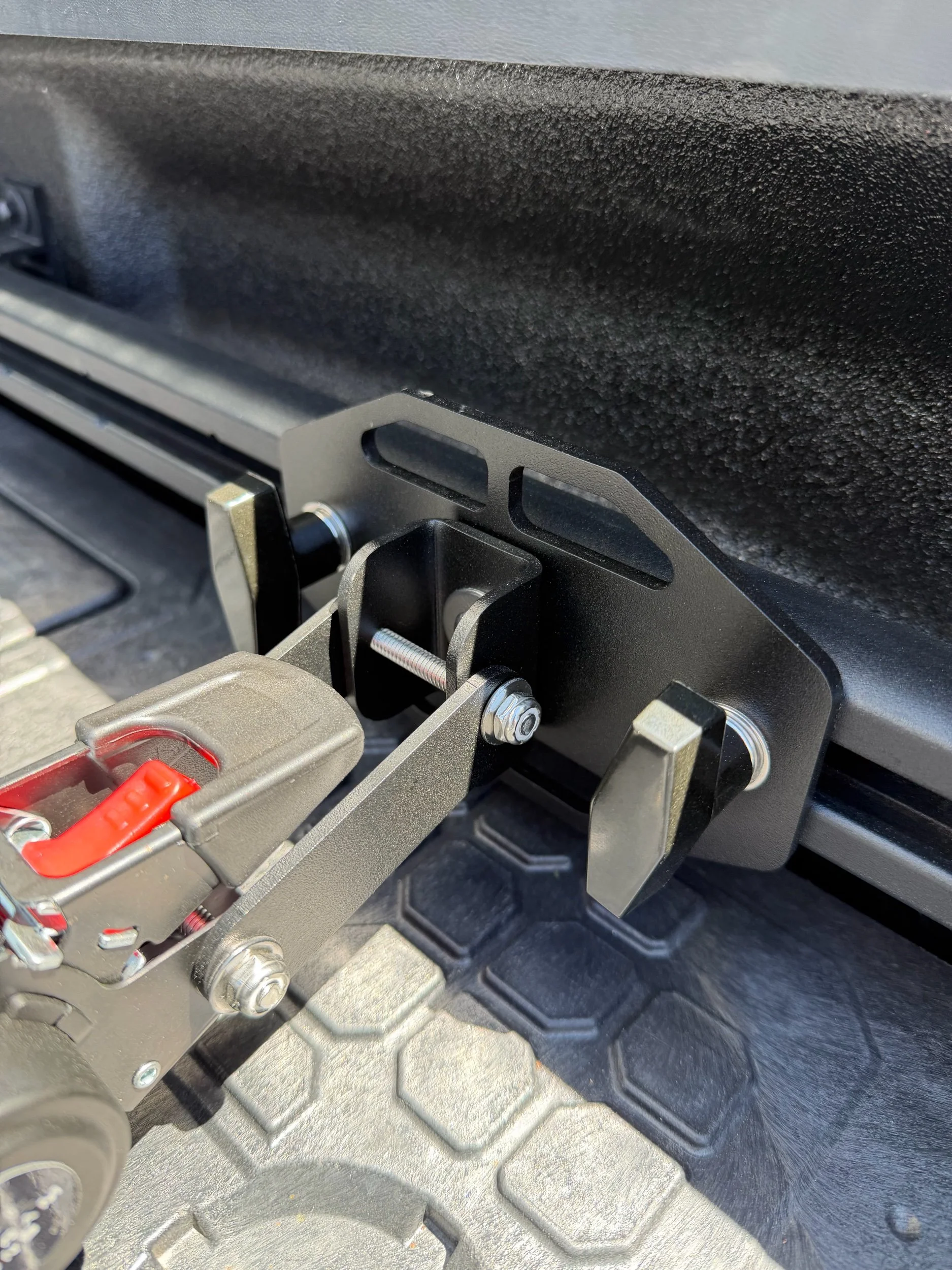 Tie Down Bed Rail Kit mounted to Ram OEM bed utility rails with retractable ratchet strap attached.