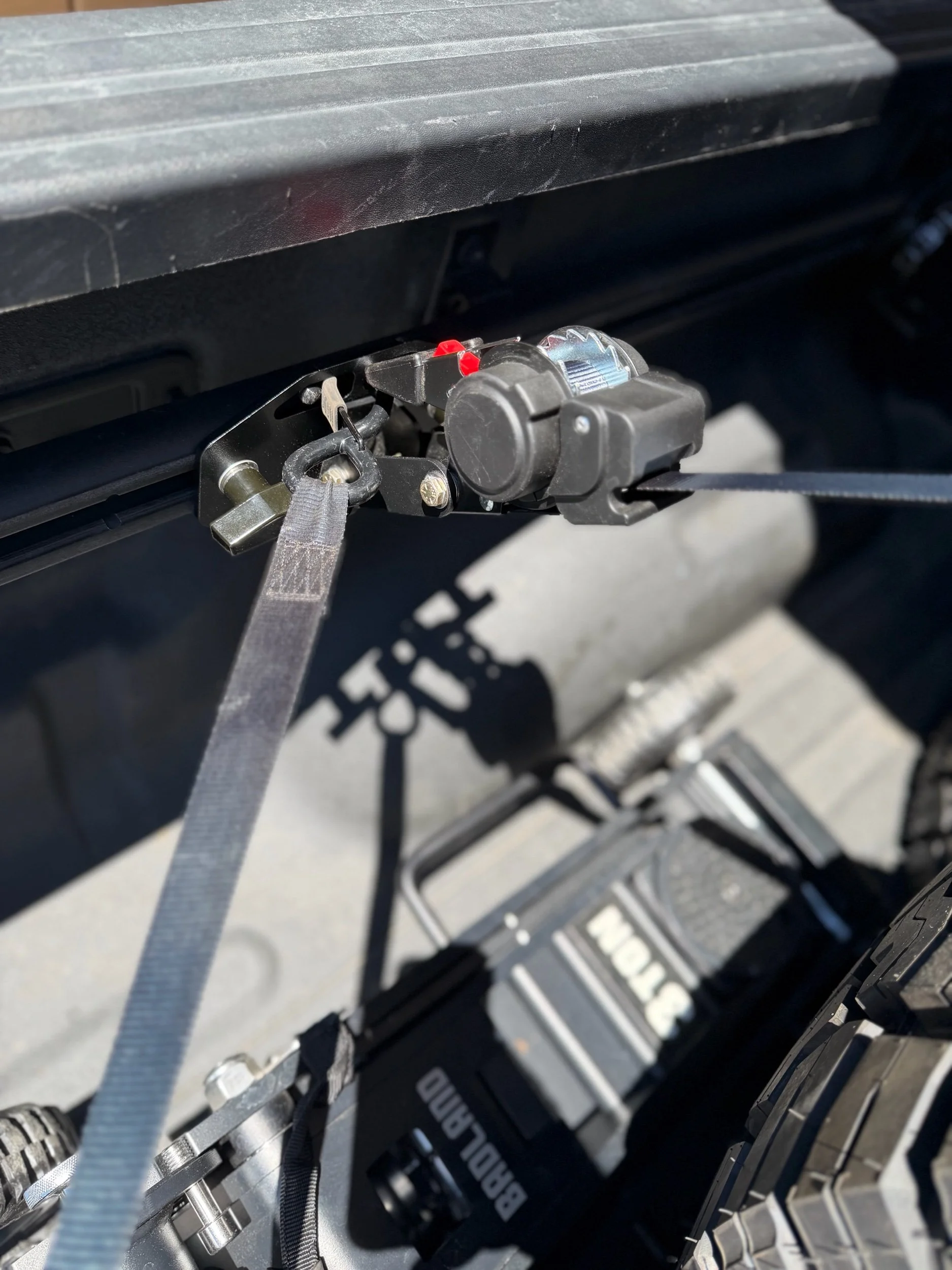 Tie Down Bed Rail Kit securing cargo with a retractable ratchet strap on Ram OEM bed utility rails.