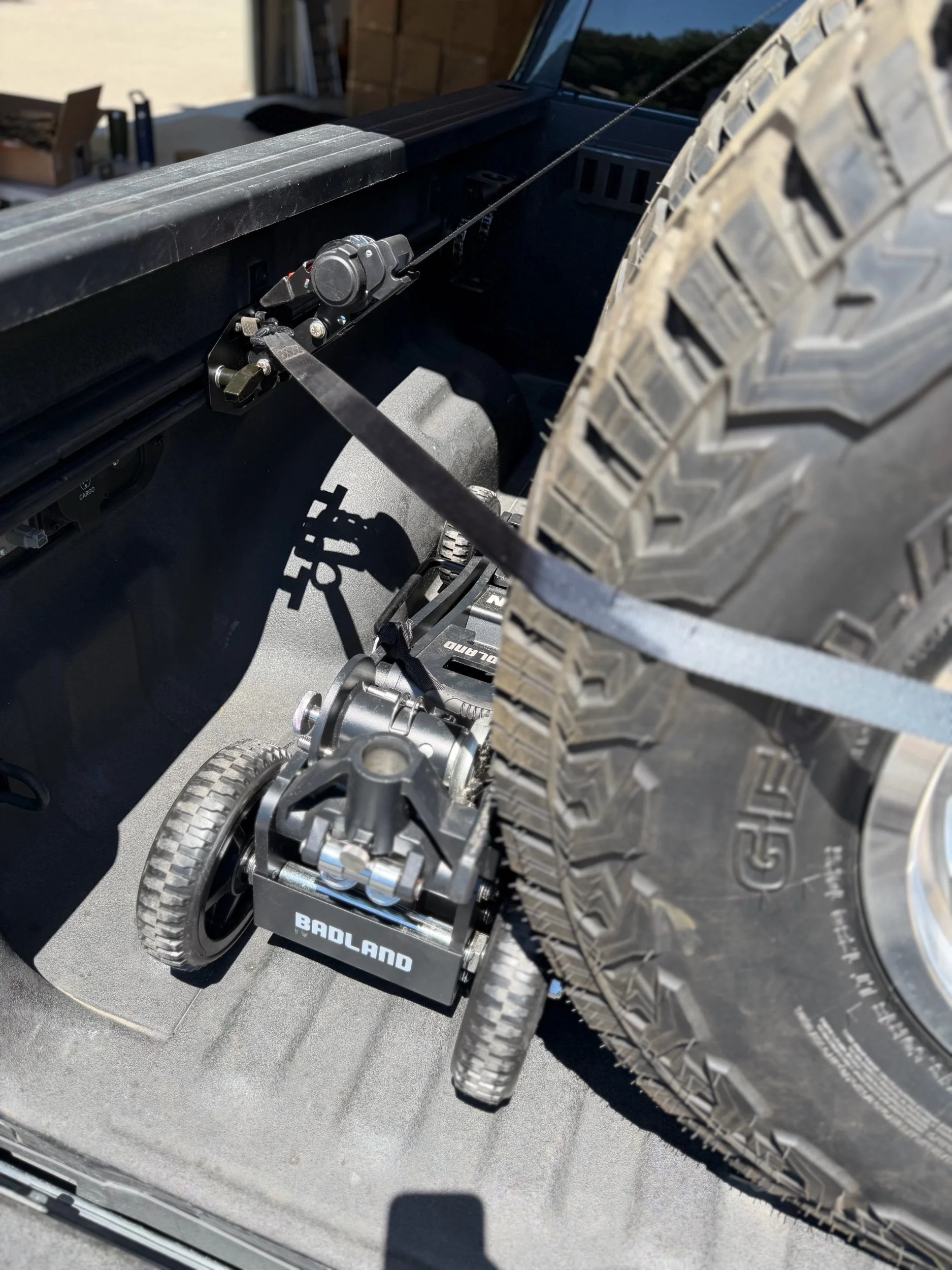 Tie Down Bed Rail Kit securing a spare tire and cargo on Ram OEM bed utility rails.
