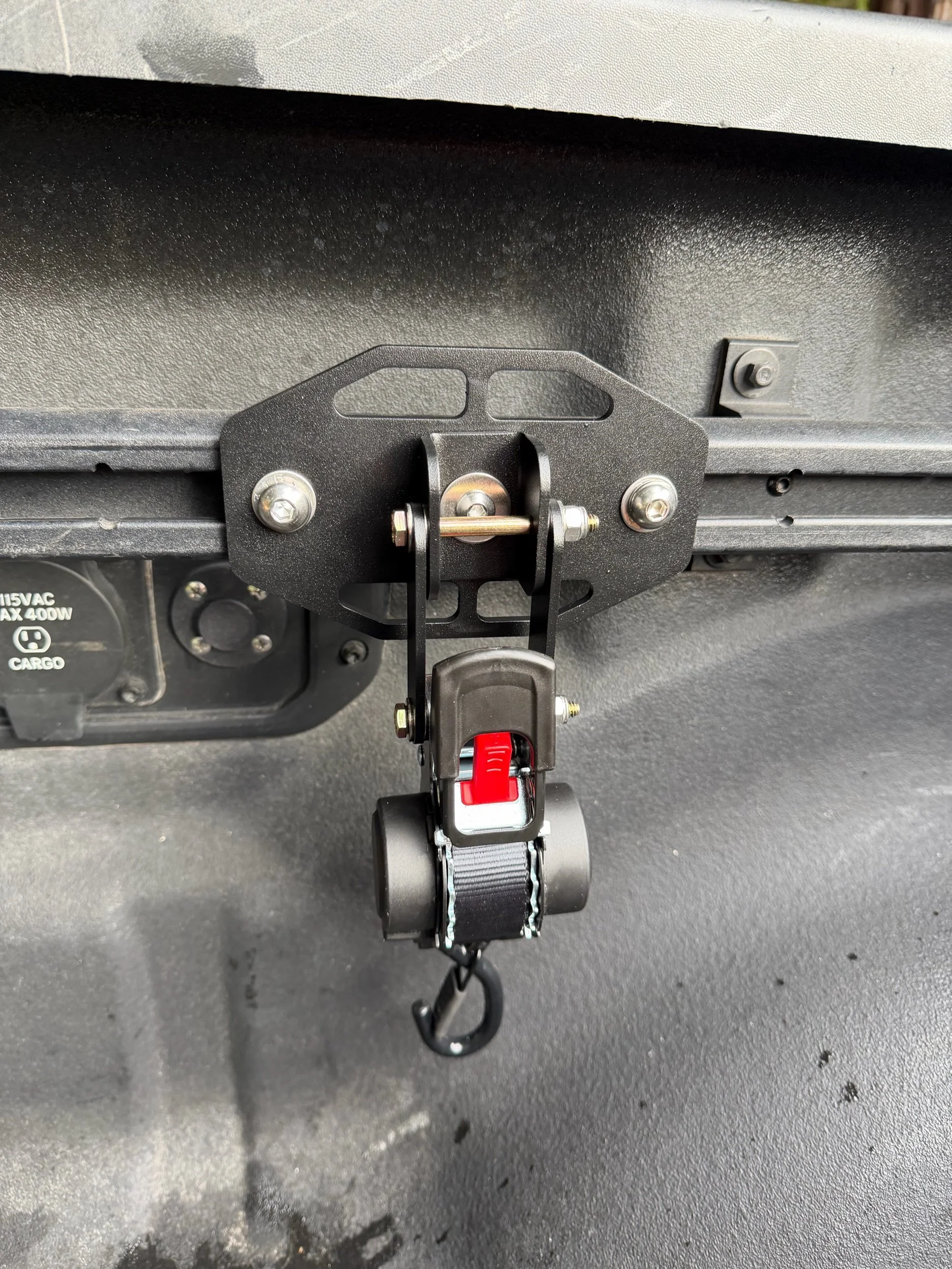 Tie Down Bed Rail Kit mounted to Ram OEM bed utility rails with retractable ratchet strap attached.