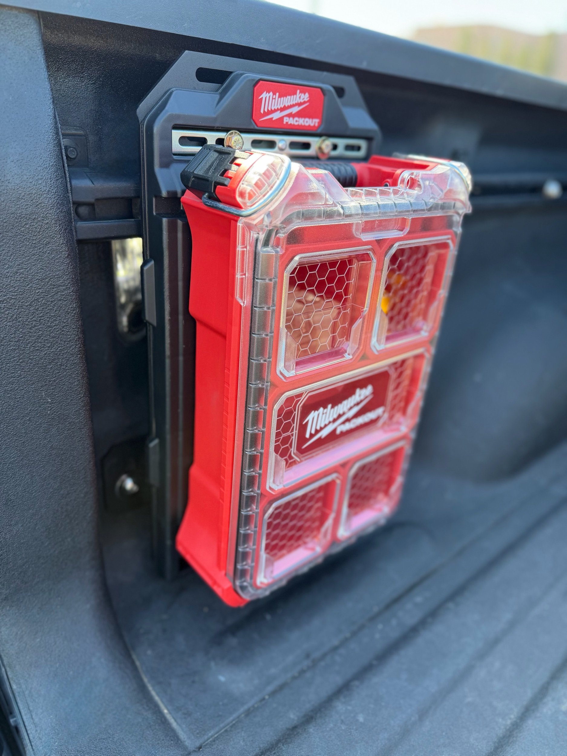 Milwaukee Packout organizer mounted to the Baja Ram Runs Molle Panel Bed Rail System installed on the OEM bed utility rail of a 2019+ Ram 1500 truck.