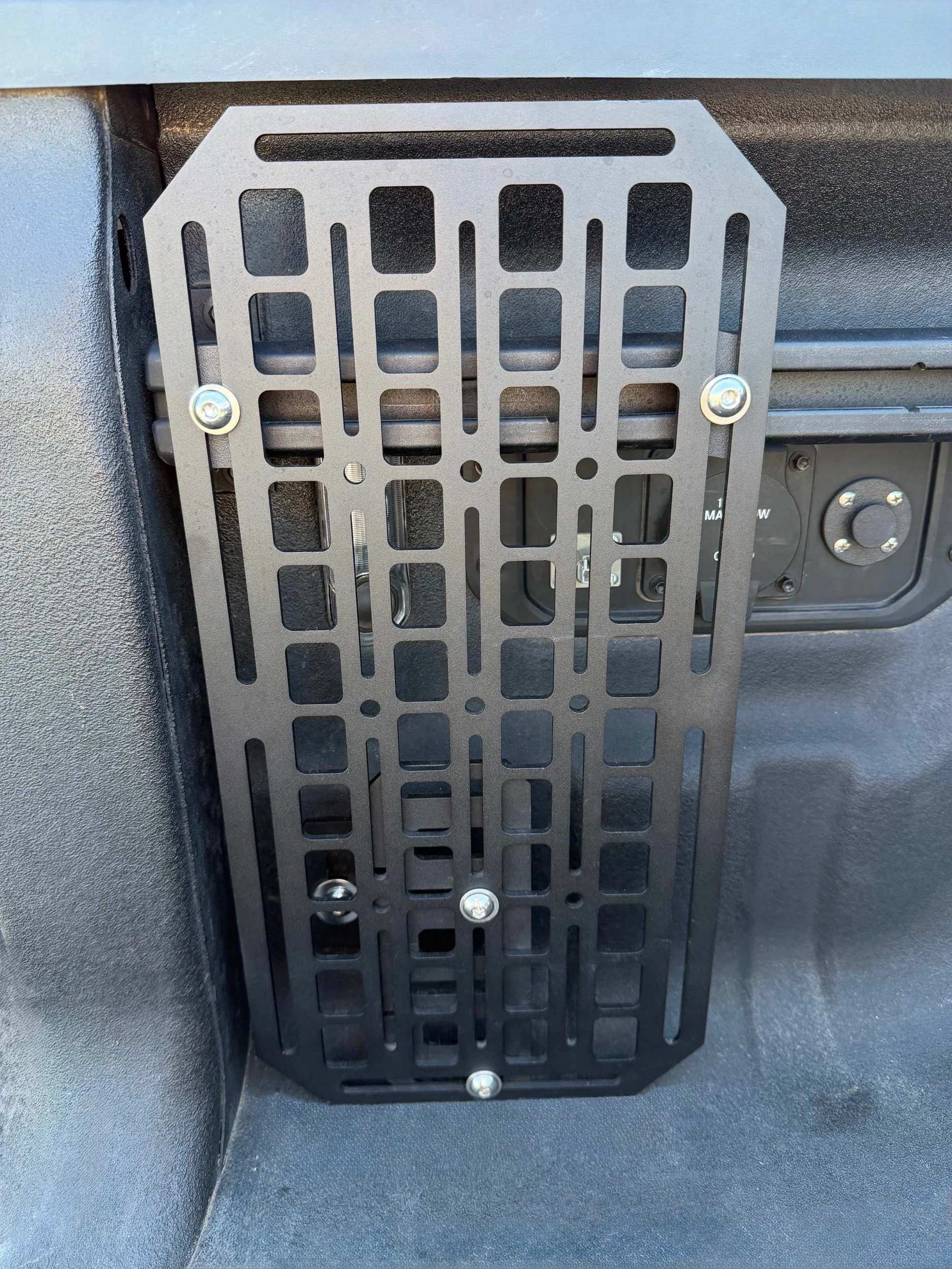 Black 10 x 20-inch aluminum Molle Panel Bed Rail System mounted vertically to the OEM bed utility rail in a 2019+ Ram 1500 truck bed.