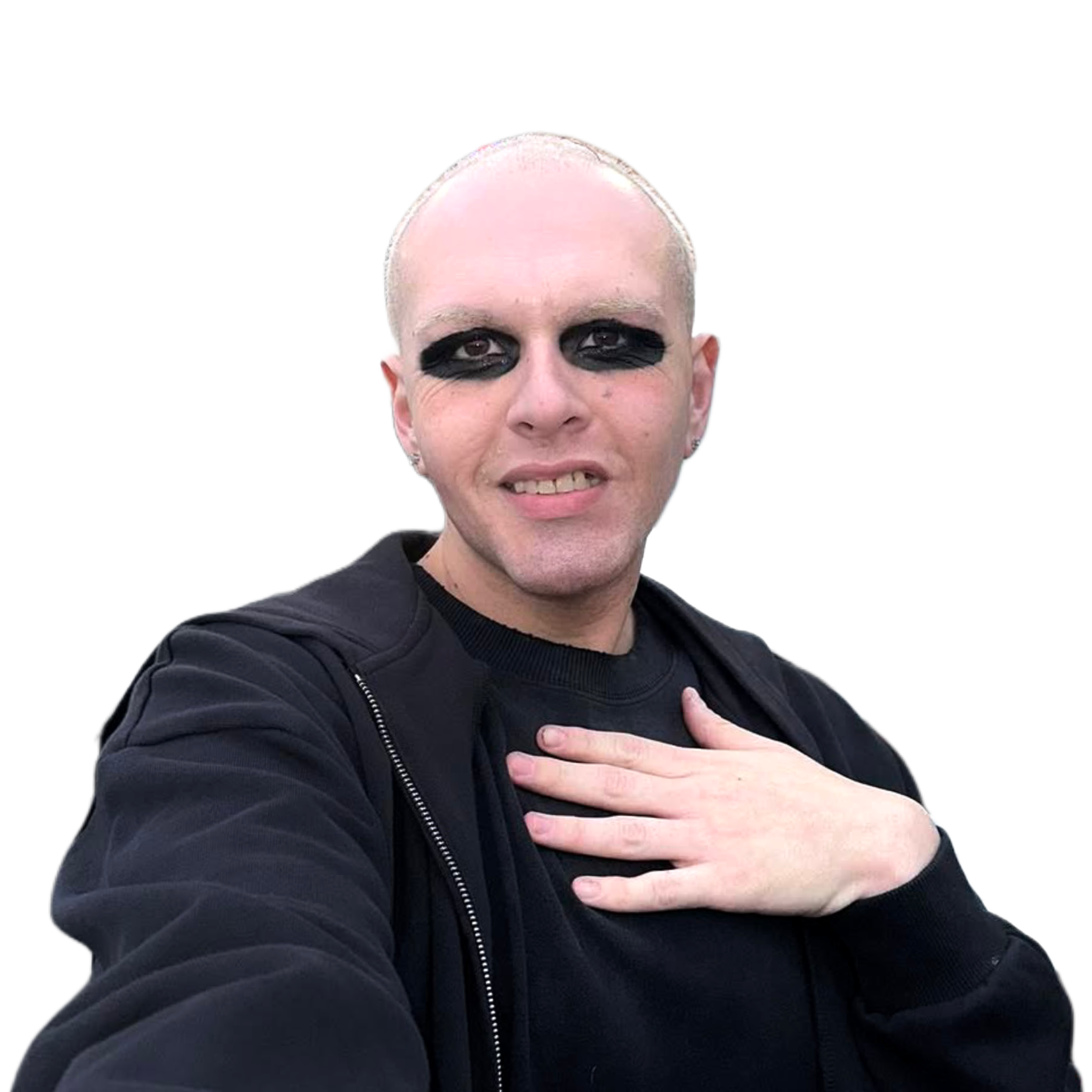 A person with short blond hair wearing black eyeshadow and a black jacket, making a gesture with their hand over their chest.
