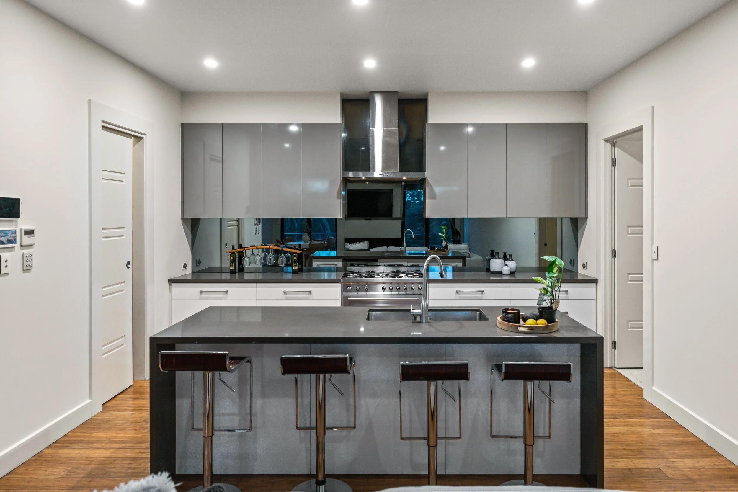 Modern kitchen with gray cabinets, stainless steel appliances, and a gray island with three bar stools.