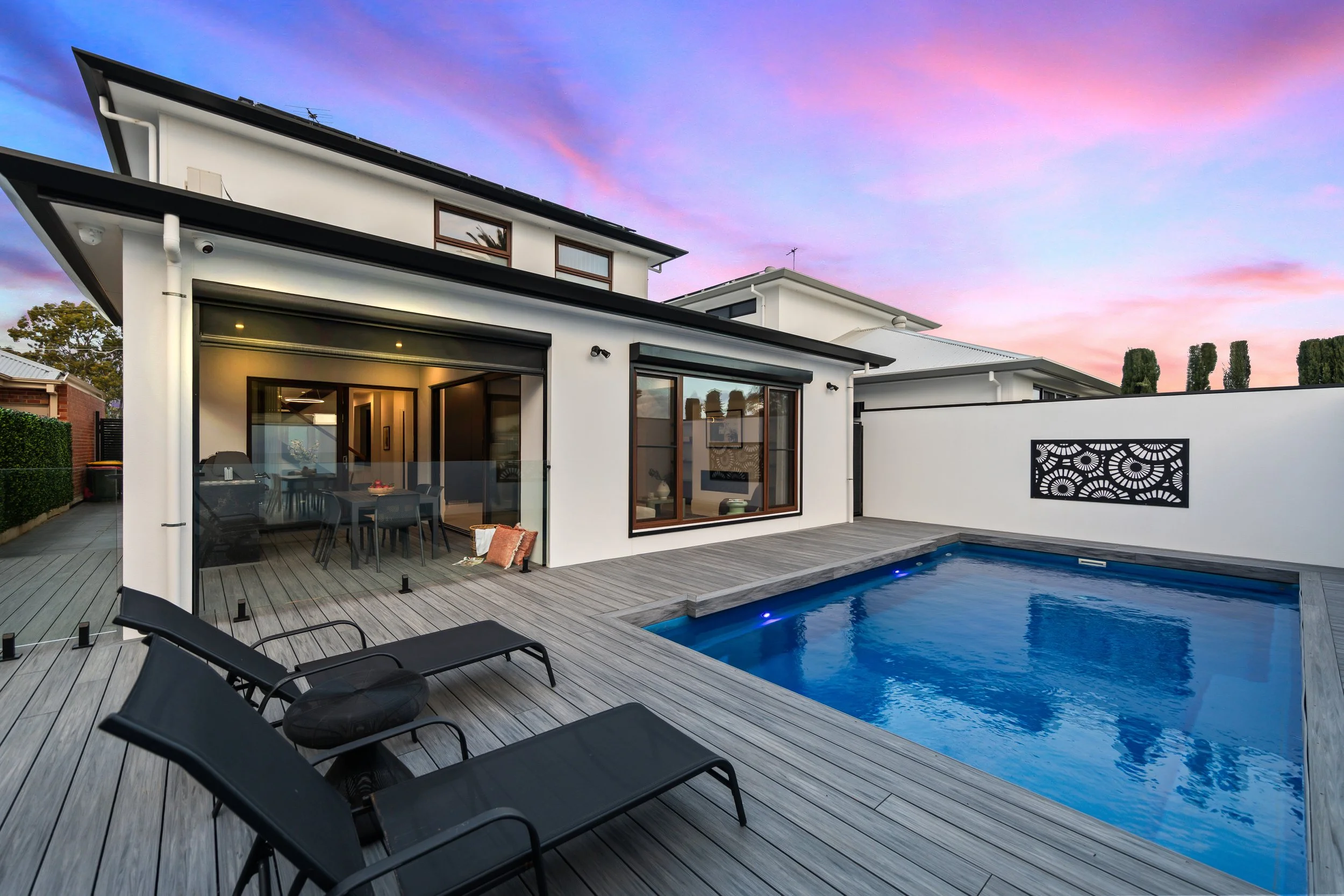 Modern house with a swimming pool and outdoor seating area at sunset.