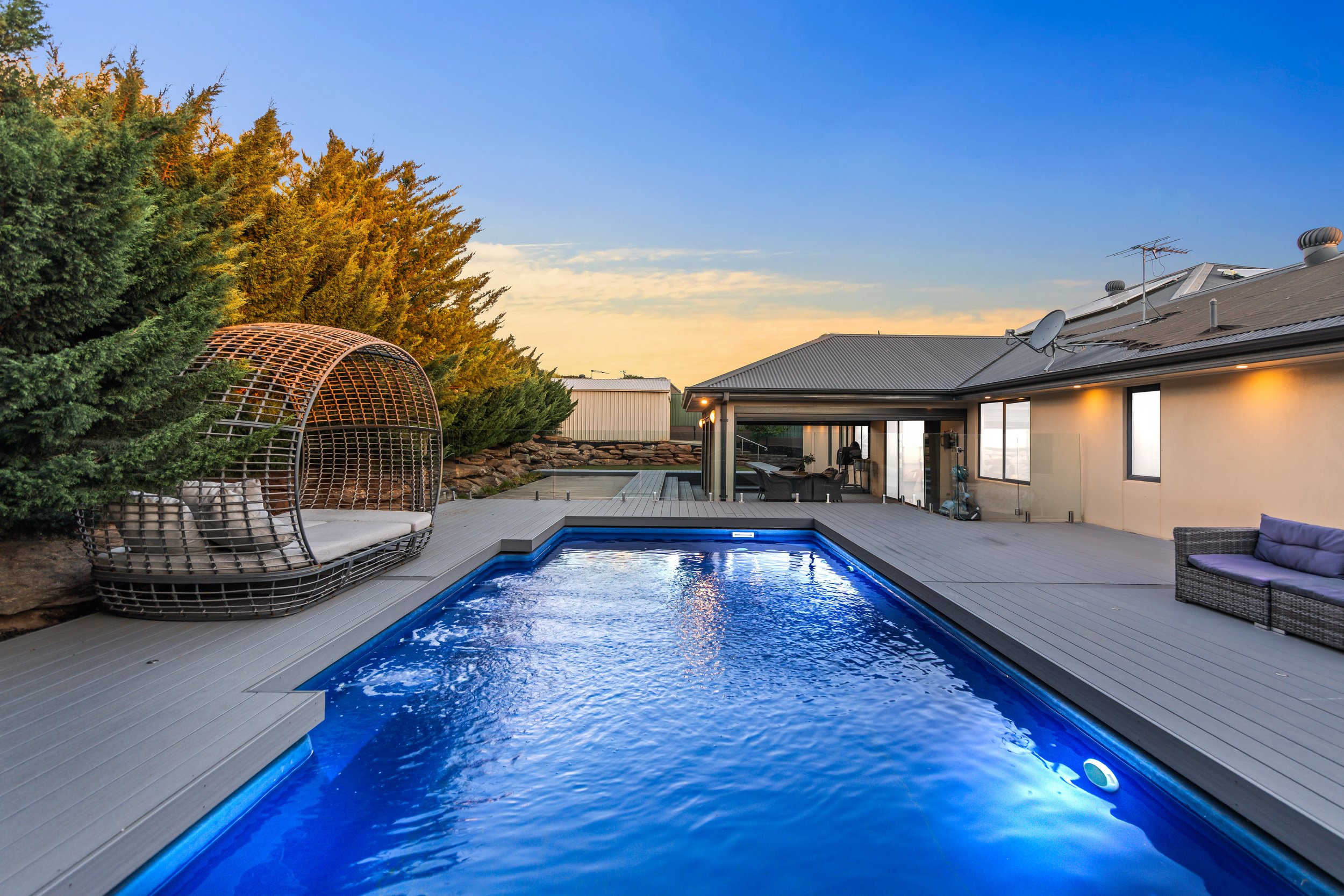 Backyard with a swimming pool, outdoor seating, and a patio at sunset