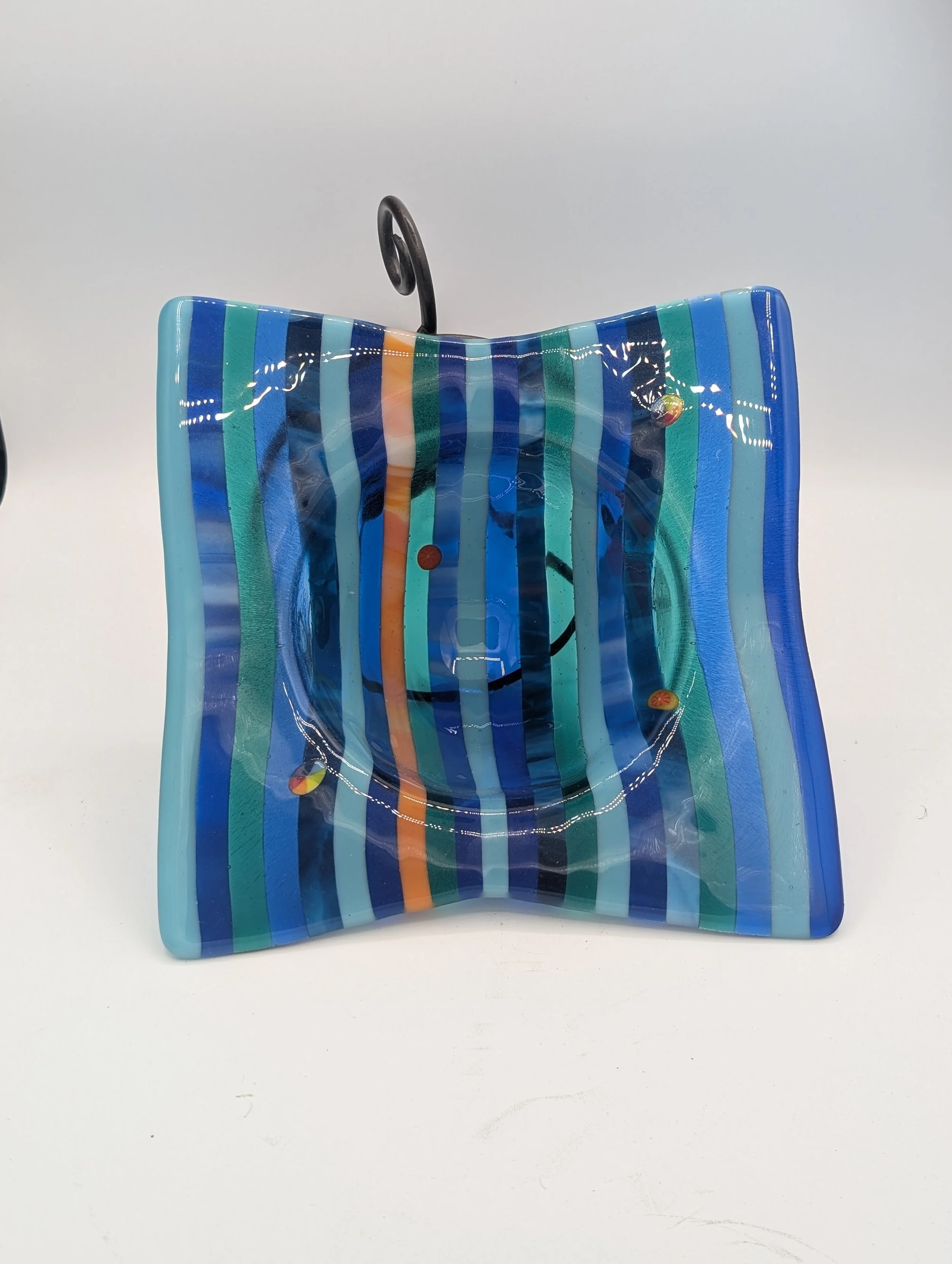 Ocean Ribbon fused glass vessel lit from the front with navy, cobalt, turquoise and teal stripes