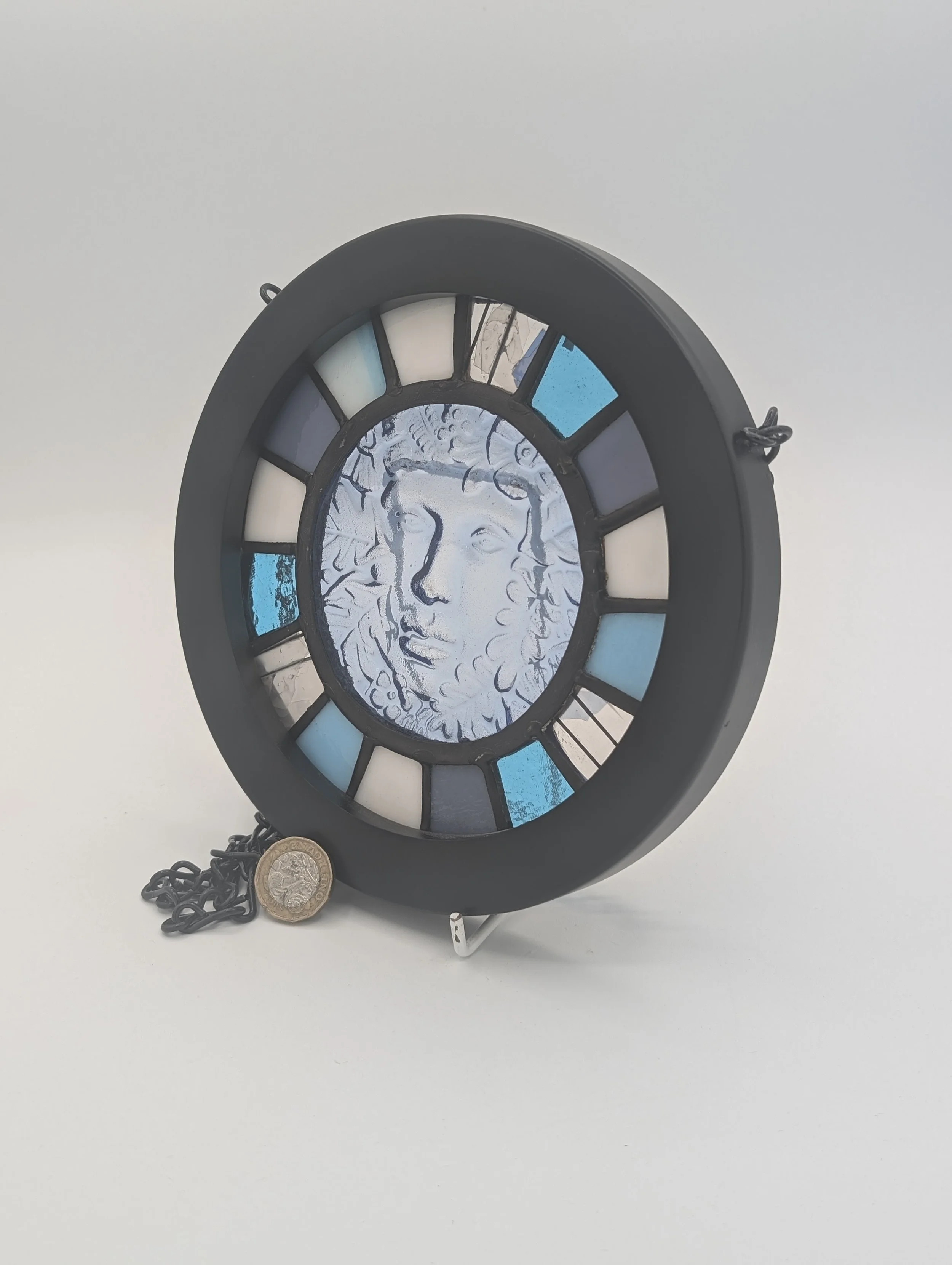 Three-quarter view of Woodland Muse showing the depth of its matte black frame, with £1 coin for scale
