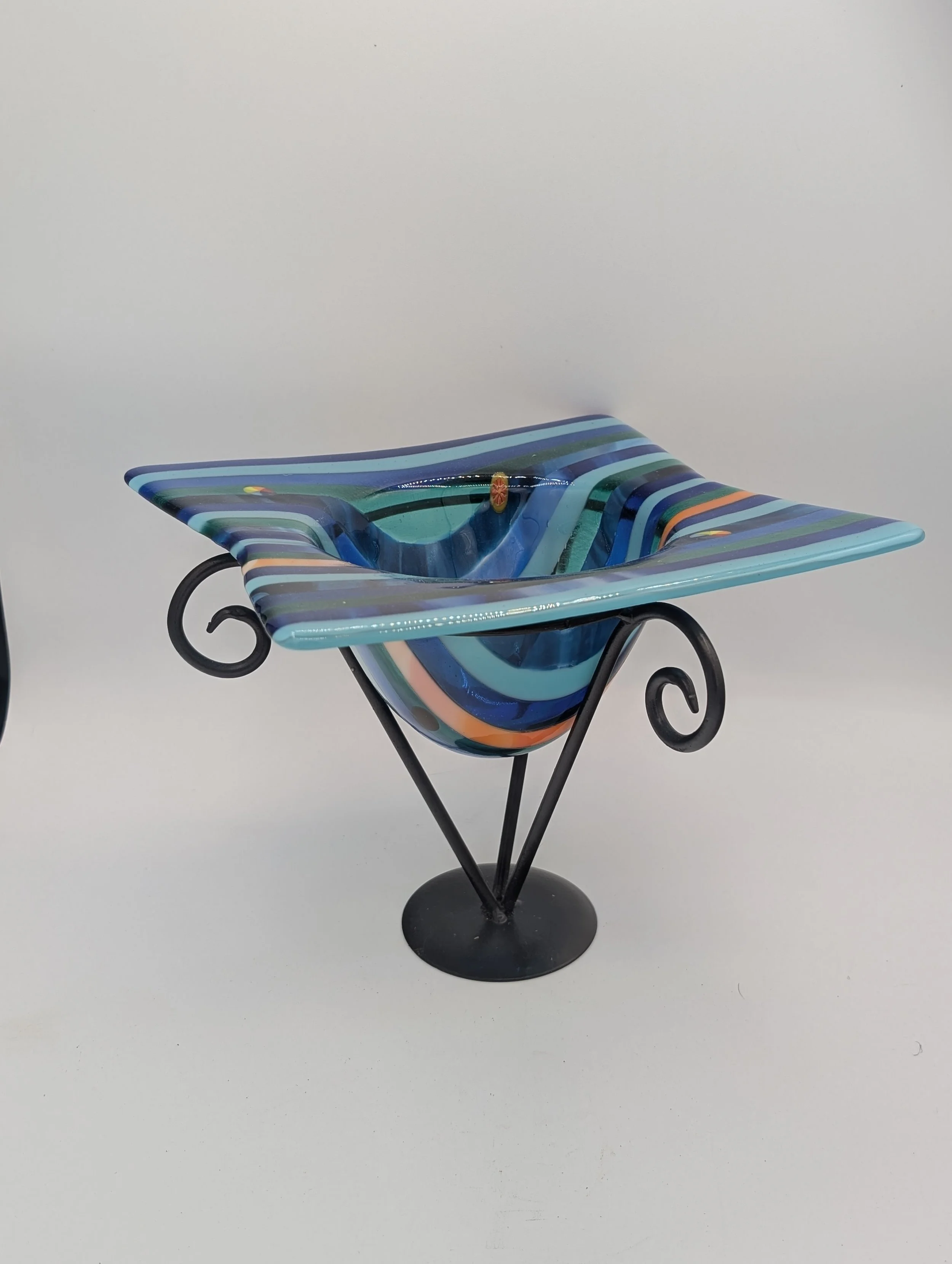 Ocean Ribbon fused glass vessel in a three-quarter view on a black metal stand