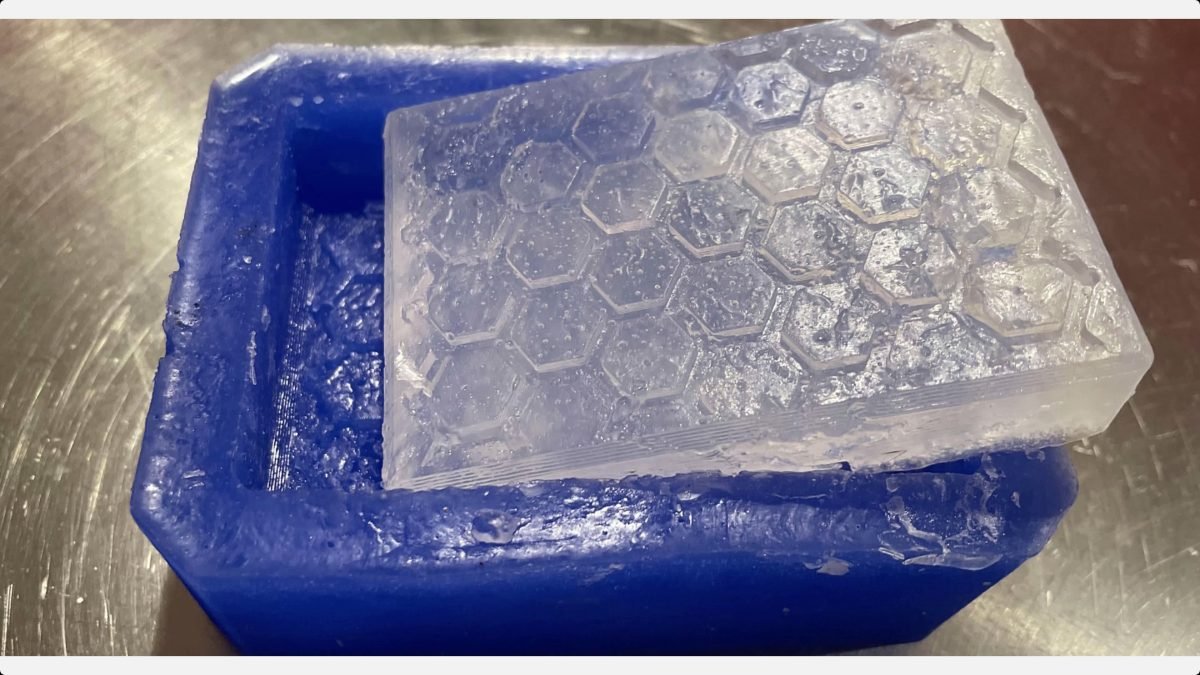 Translucent honeycomb-patterned soap bar resting diagonally across a blue silicone mold.