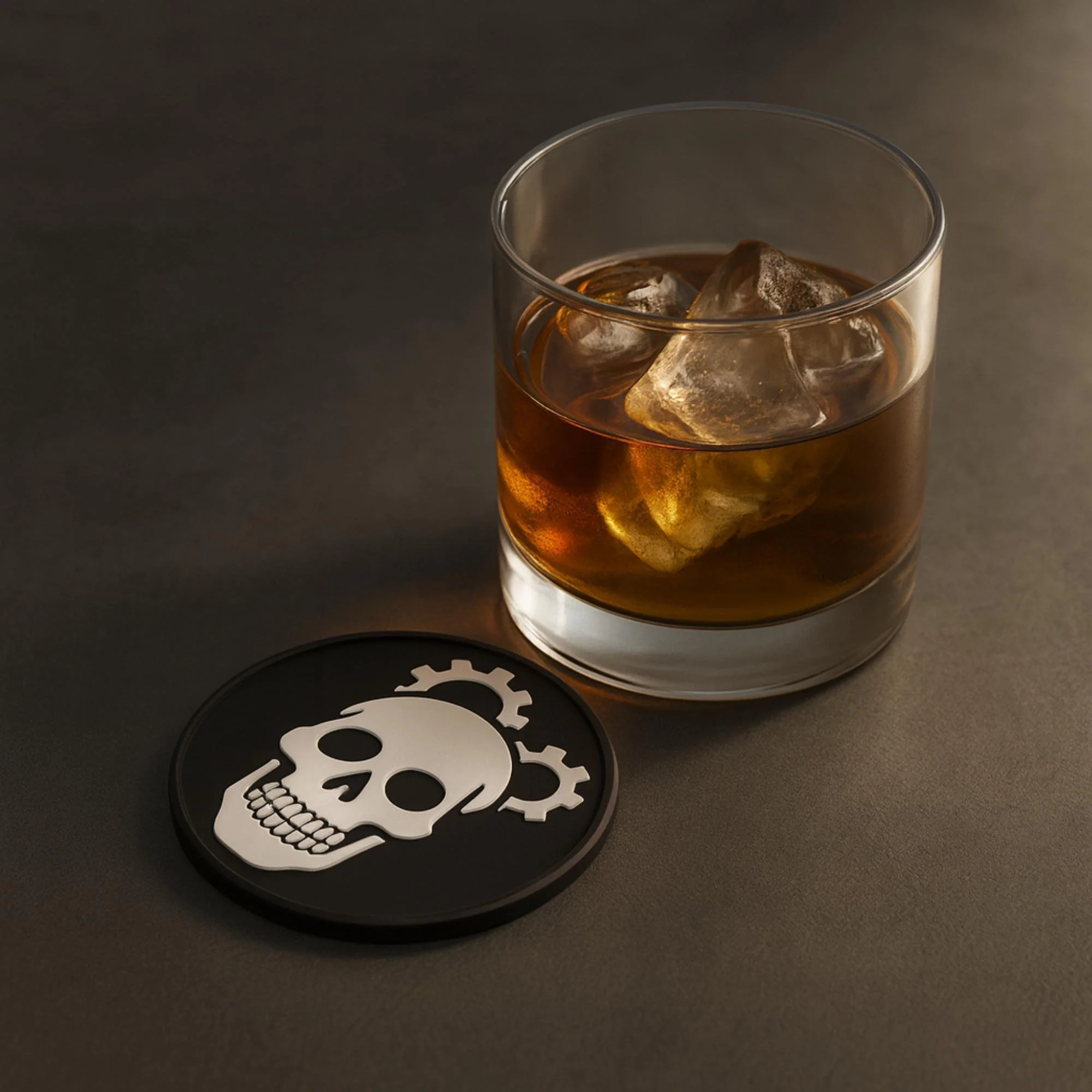 3D-printed drink coaster with a white skull and mechanical gear symbols, shown beside a glass of iced drink on a matte dark surface.