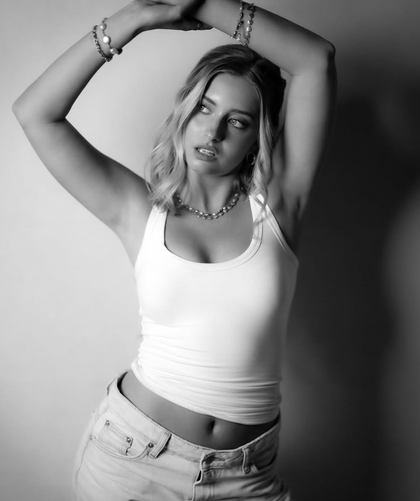 Woman in off-shoulder black dress posing against a white background