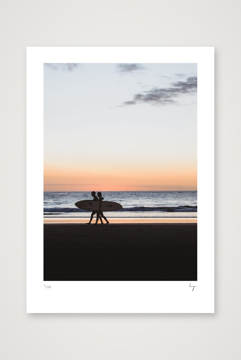 A couple walking with surfboards down the beach in Costa Rica