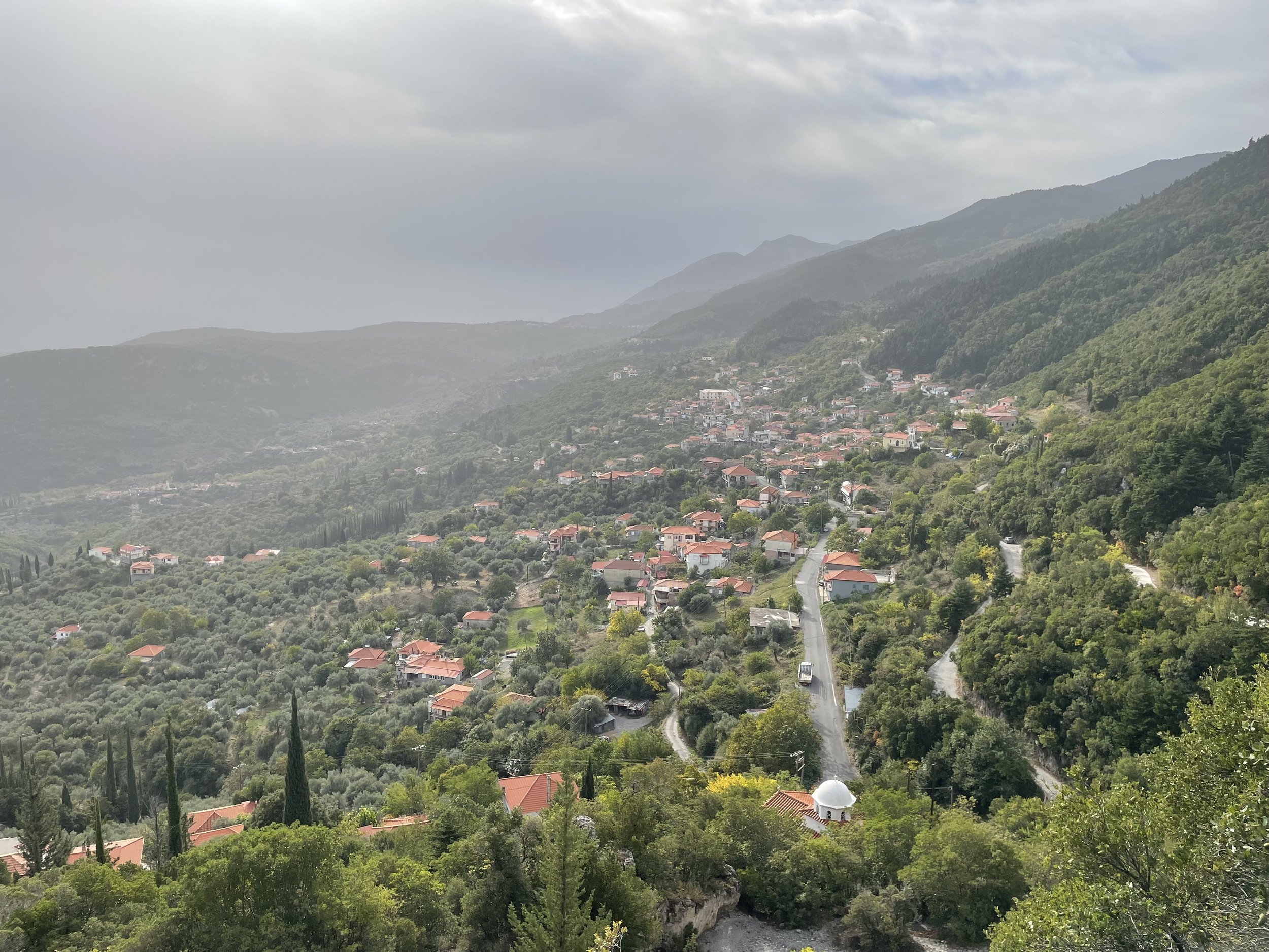 View of Logkanikos village near the Metropoulos  family Ygeia grove, with stone houses and surrounding olive‑covered hills
