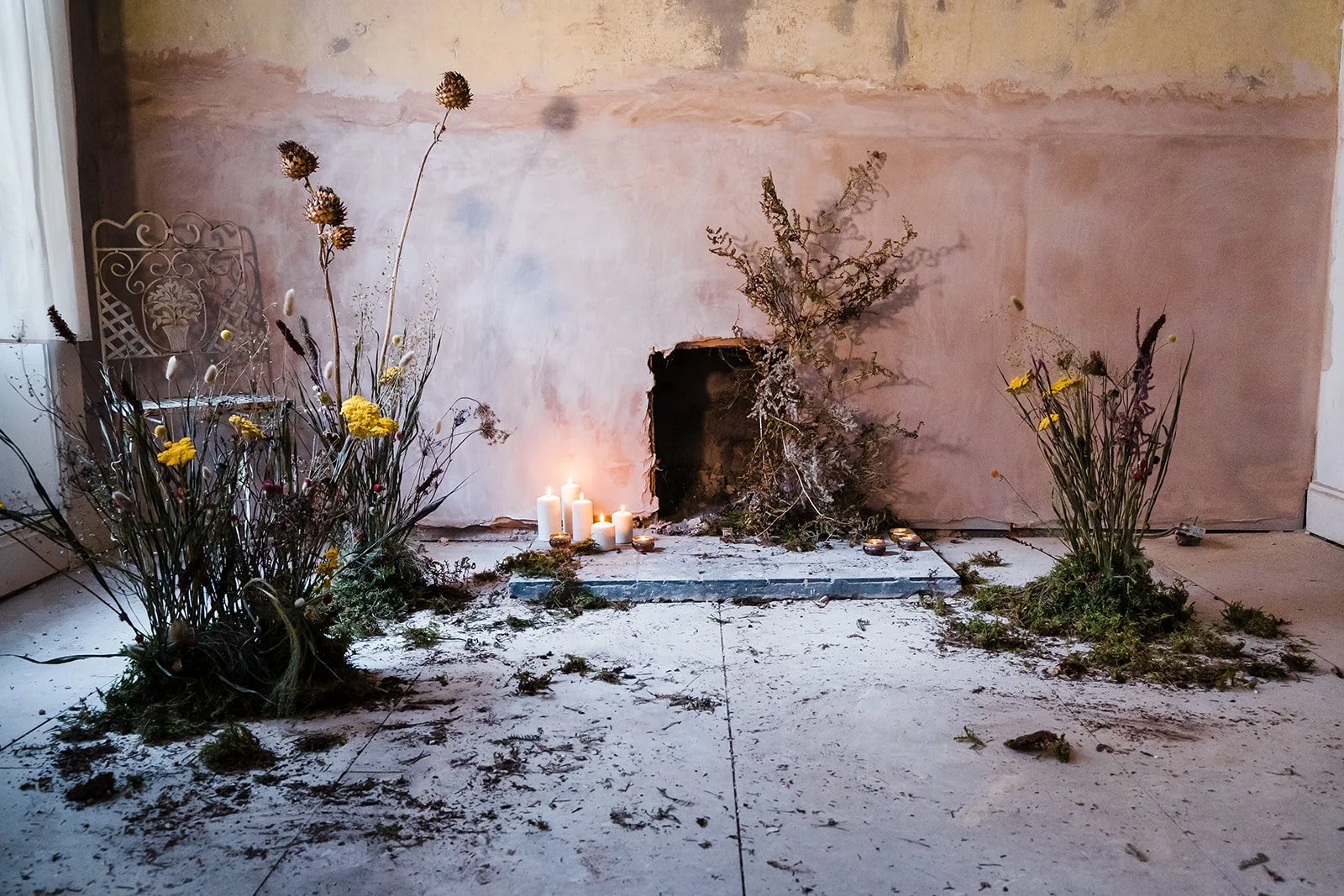 Dried flower installation styled within an empty interior space featuring natural materials and soft candlelight