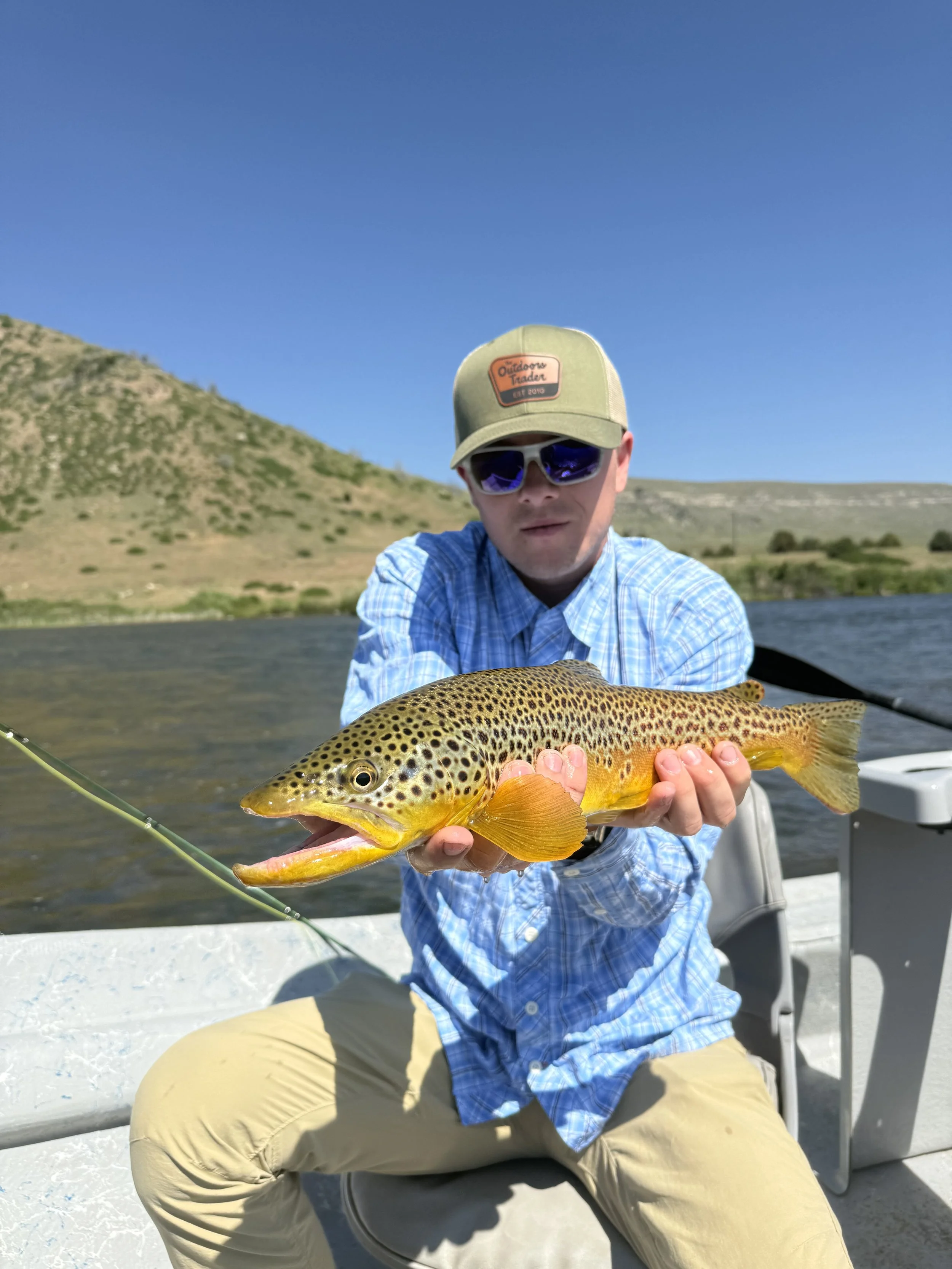 Young client holding a nice brown trout caught on a streamer on the lower Madison River on a guided fly fishing trip