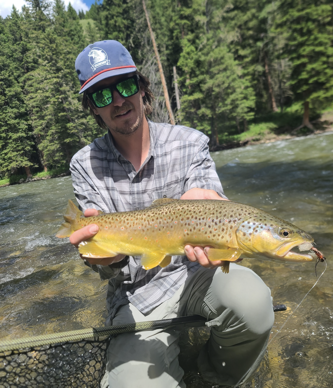 Client with a big brown trout caught on a dry fly on the Gallatin River while fly fishing.