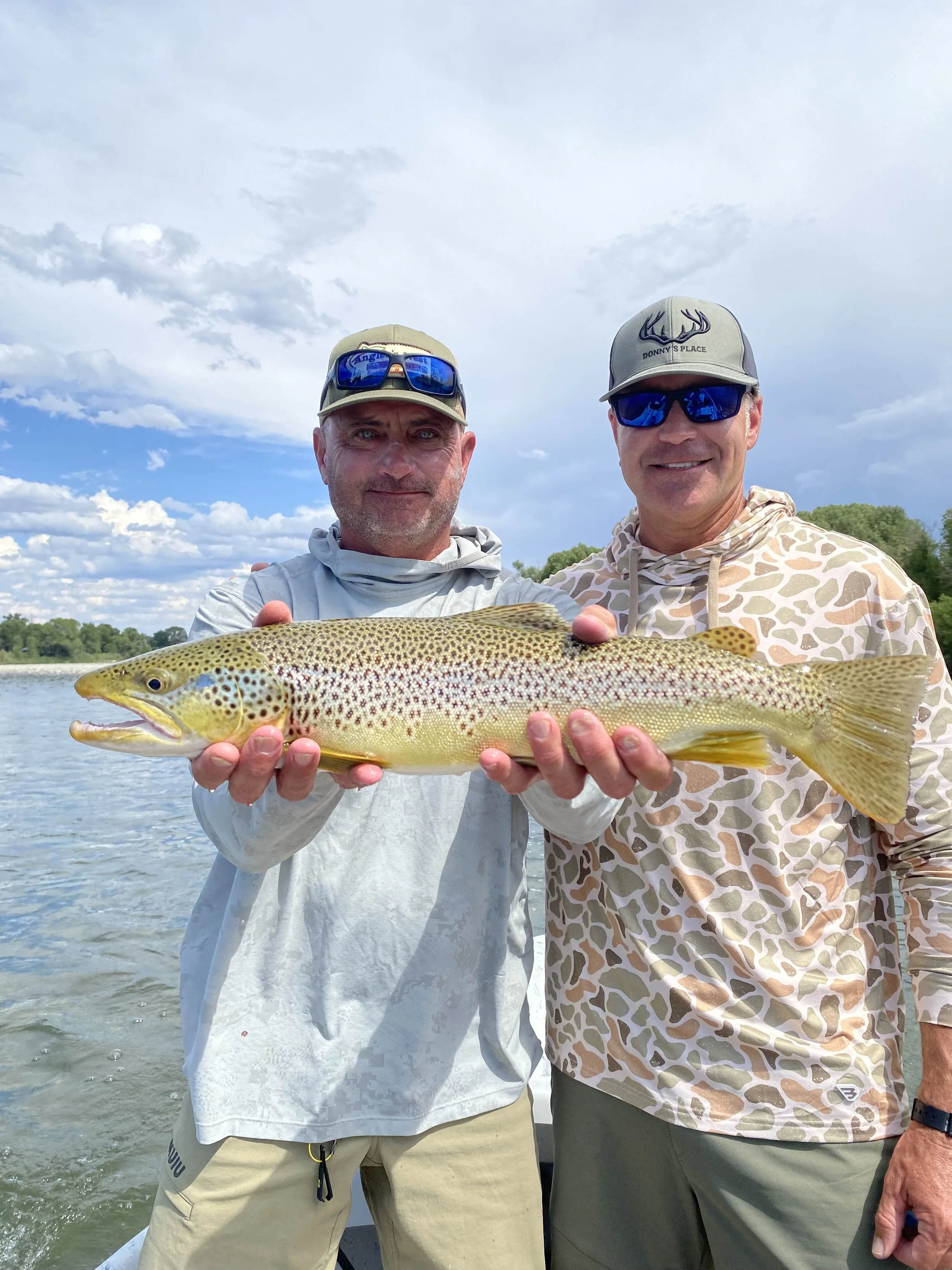 group guided fly fishing trip on the yellowstone river. clients holding a big brown trout caught on a streamer on a guided fly fishing trip
