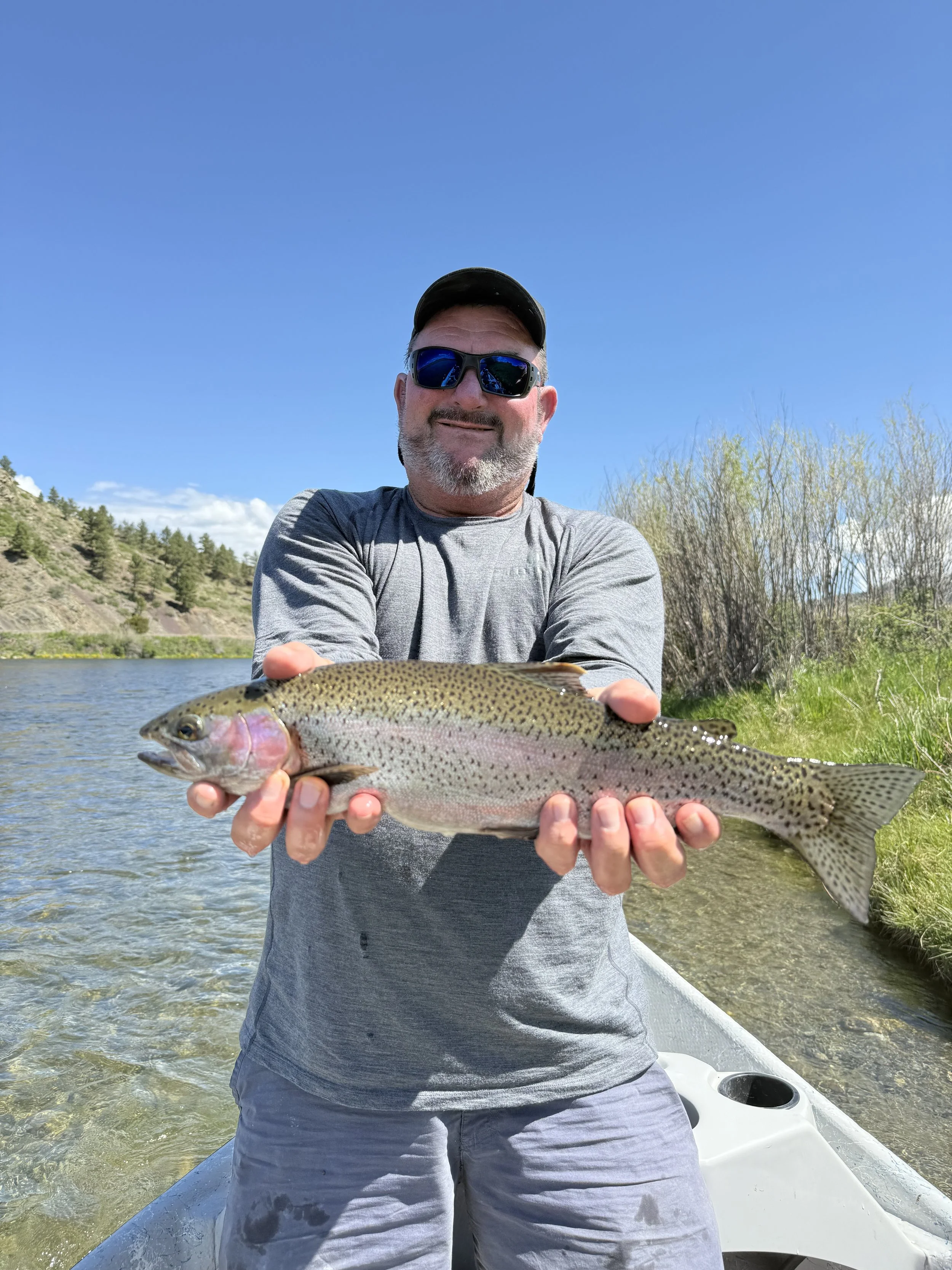 First time angler holding a big rainbow trout on a guided fly fishing trip in Bozeman Montana