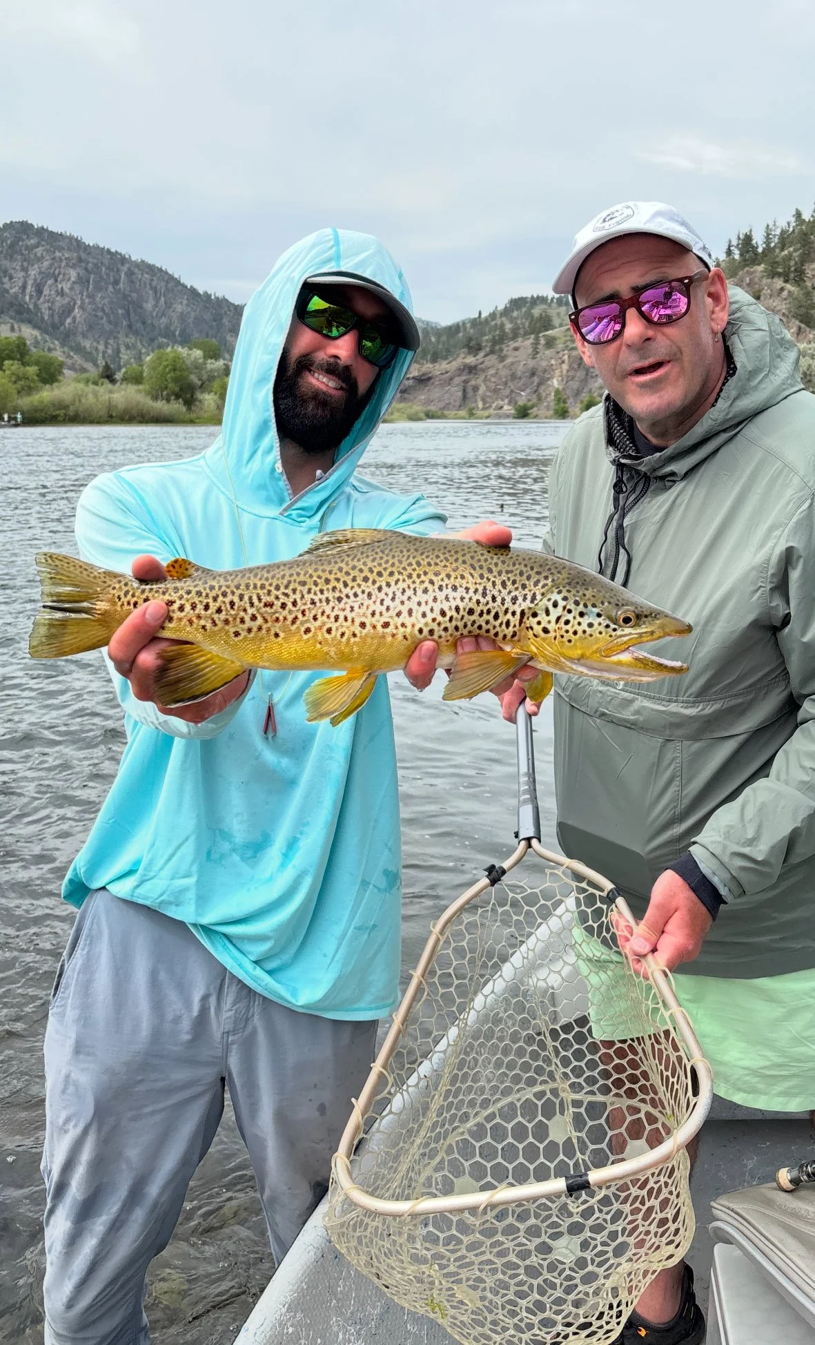 Luke Montgomery holding a large brown trout for a client on a guided fly fishing trip on the Missouri River