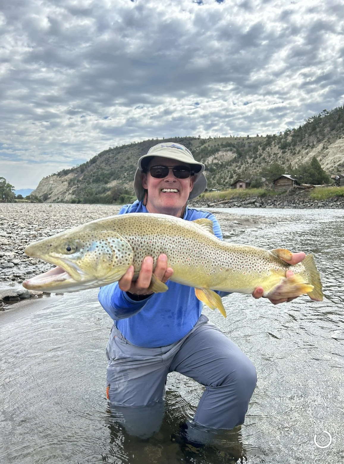 Angler holding big brown trout from the yellowstone river on a guided fly fishing trip in bozeman