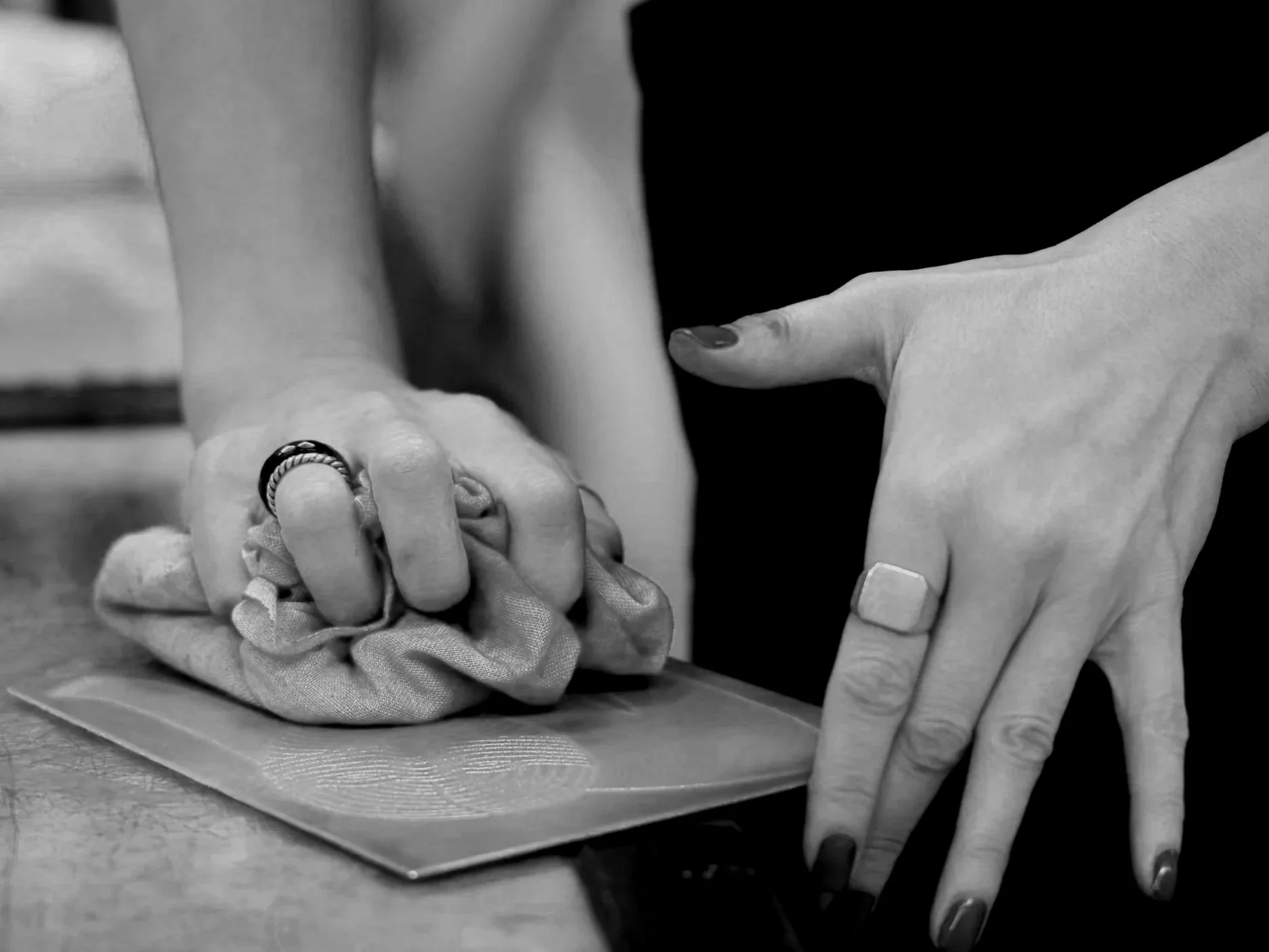 black and white image of the artist's hands up close, working on some of their art