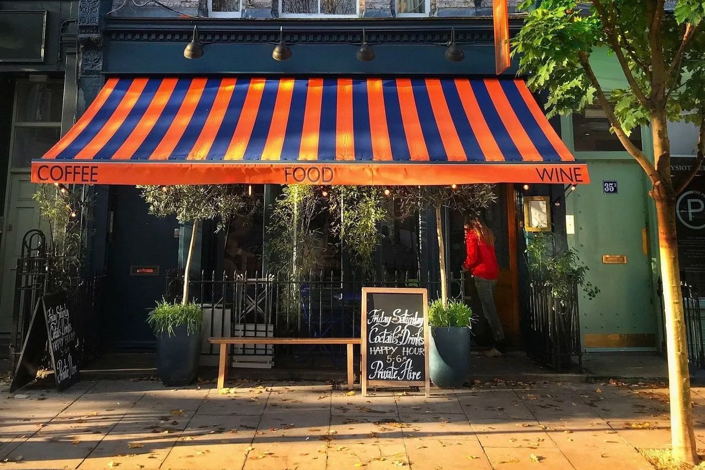 Exterior of a charming coffee shop in Notting Hill with outdoor seating, showcasing artwork on the walls