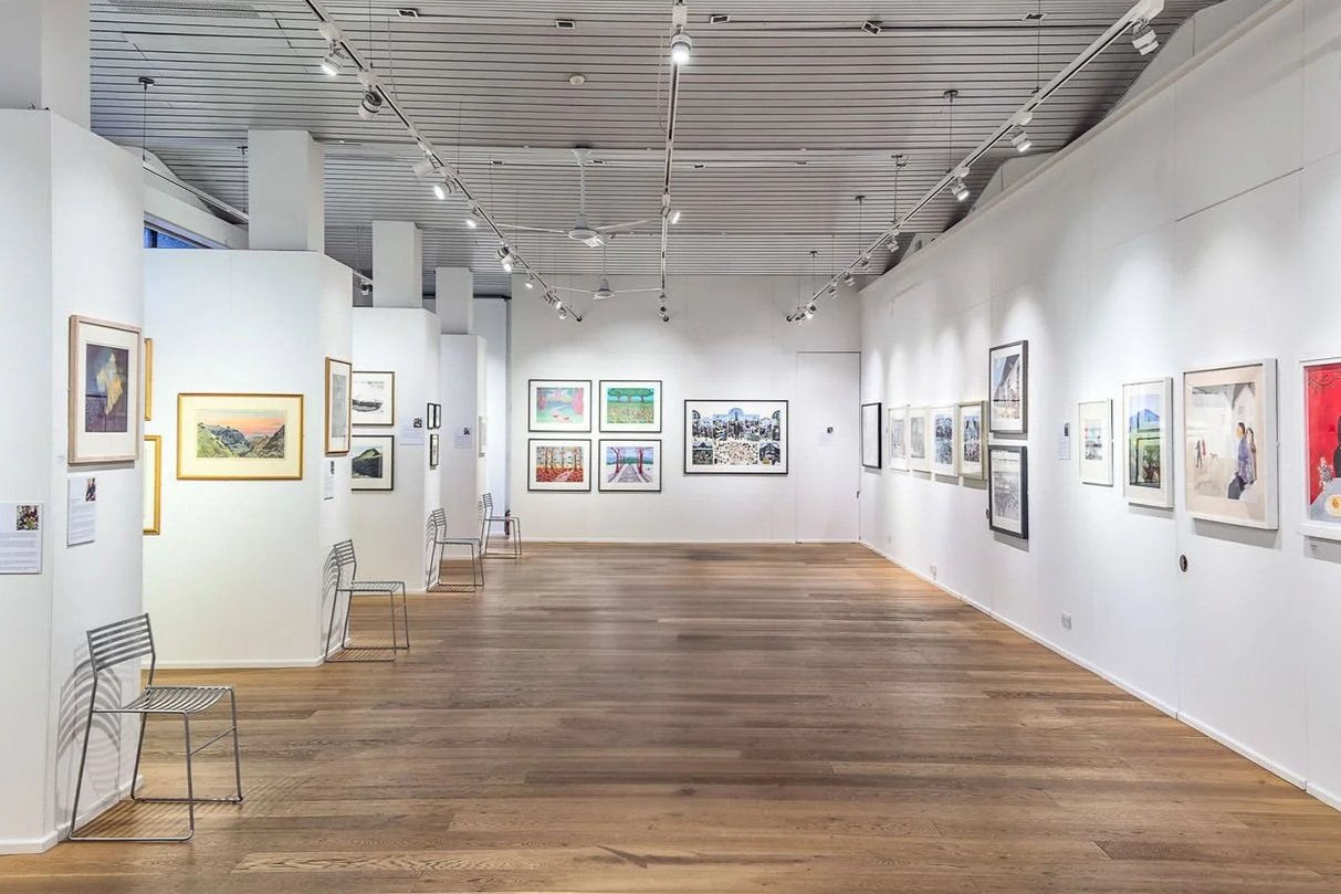 Interior of Bankside Gallery in London showcasing artworks, with visitors viewing contemporary paintings and prints on display