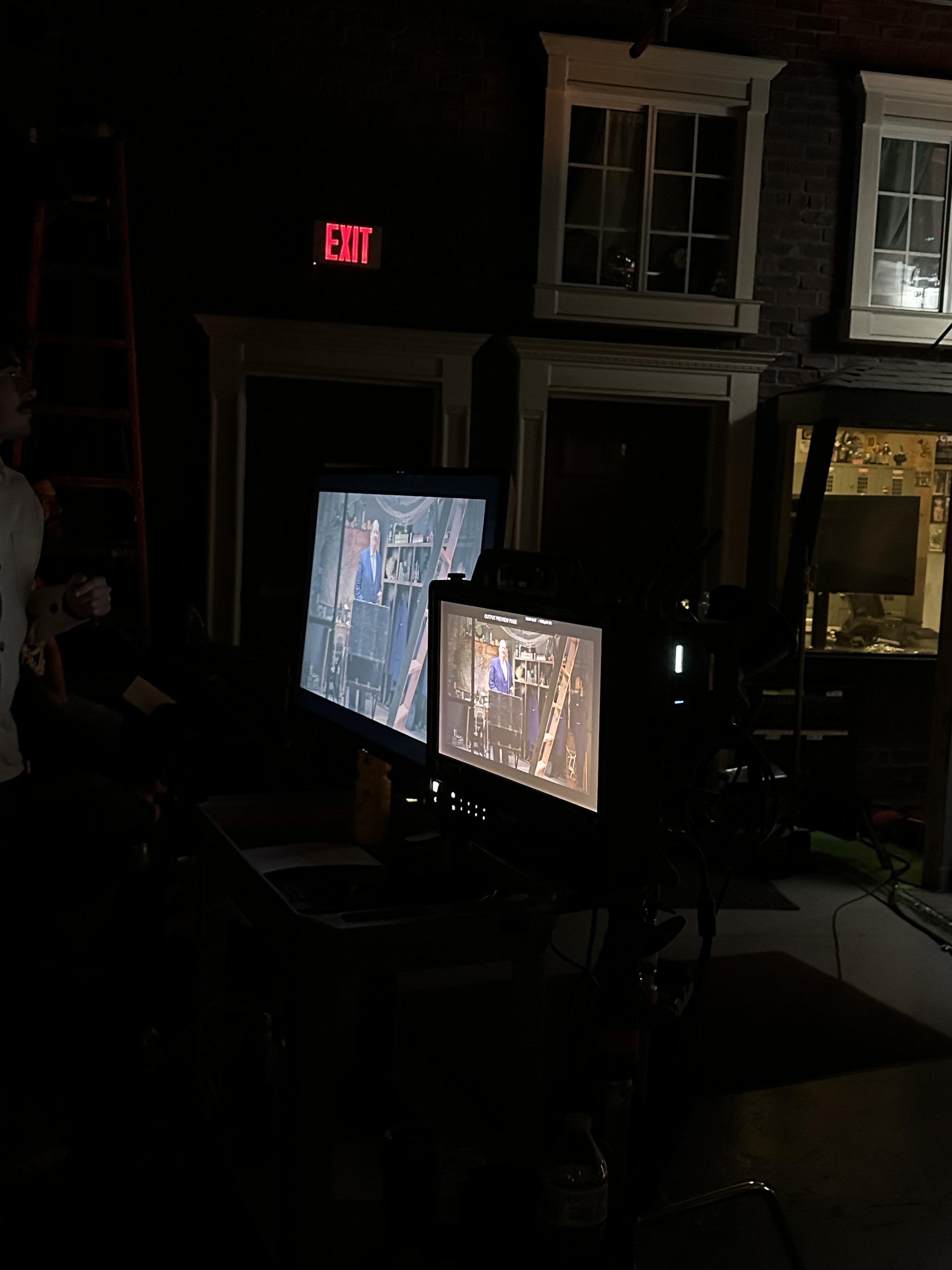 In-between takes, the gaffer and lighting crew are seen adjusting equipment for this scene.