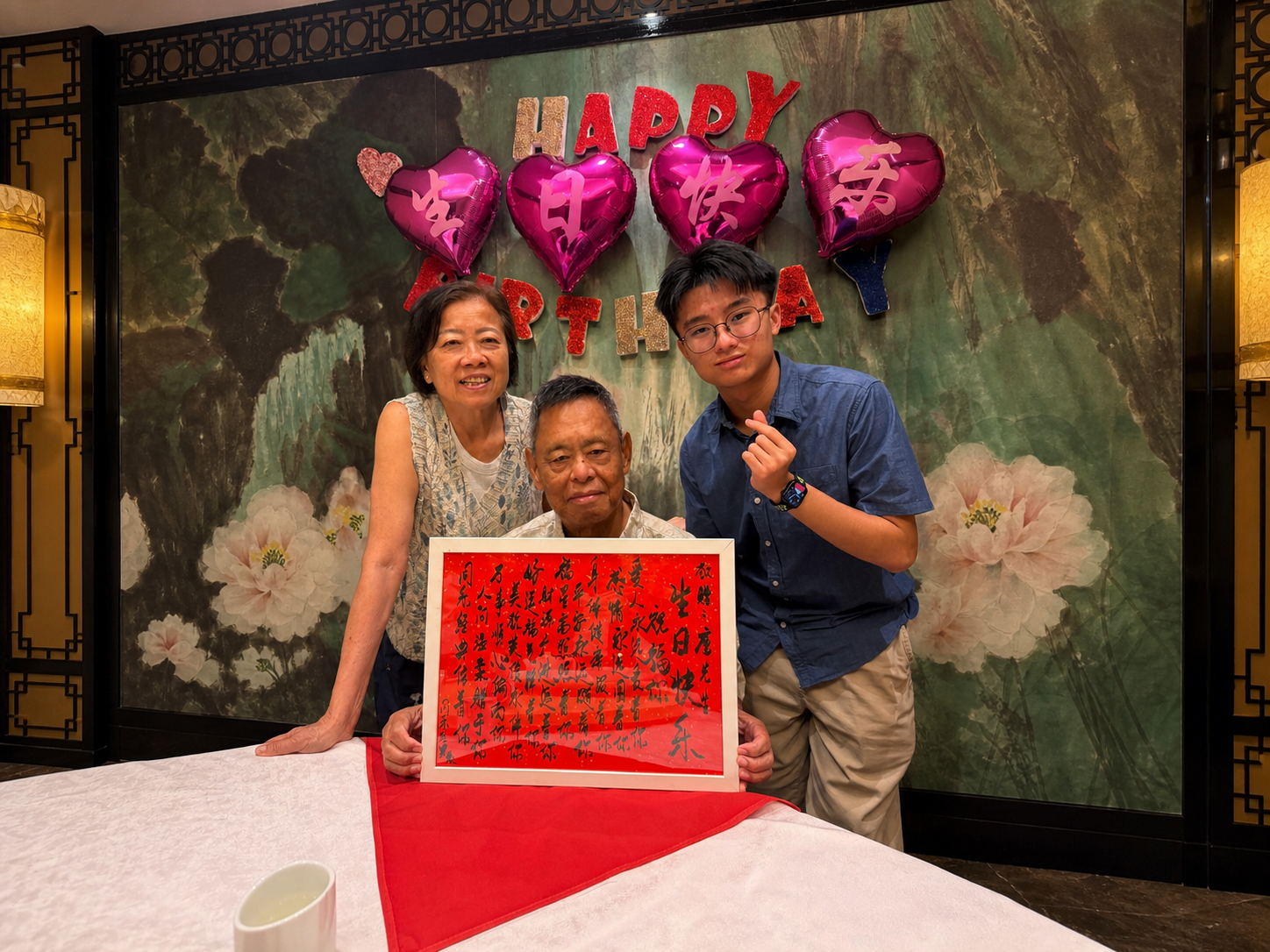 Jerome's family around his grandfather at his 78th birthday, holding a framed calligraphy poem.My grandparents and me at my grandfather's birthday,