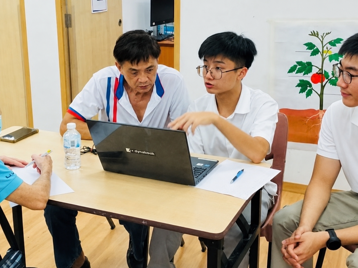 Jerome on a laptop and another volunteer, writing up a resident's case at a Meet-the-People Session.