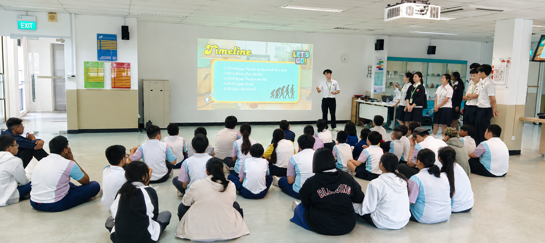 Students seated in rows facing a projector screen during a communication workshop at Grace Orchard School.