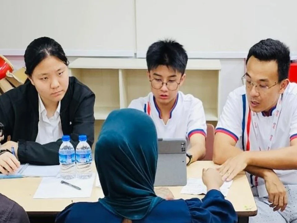 Jerome Ong helping a resident with paperwork across a table at a Meet-the-People Session.
