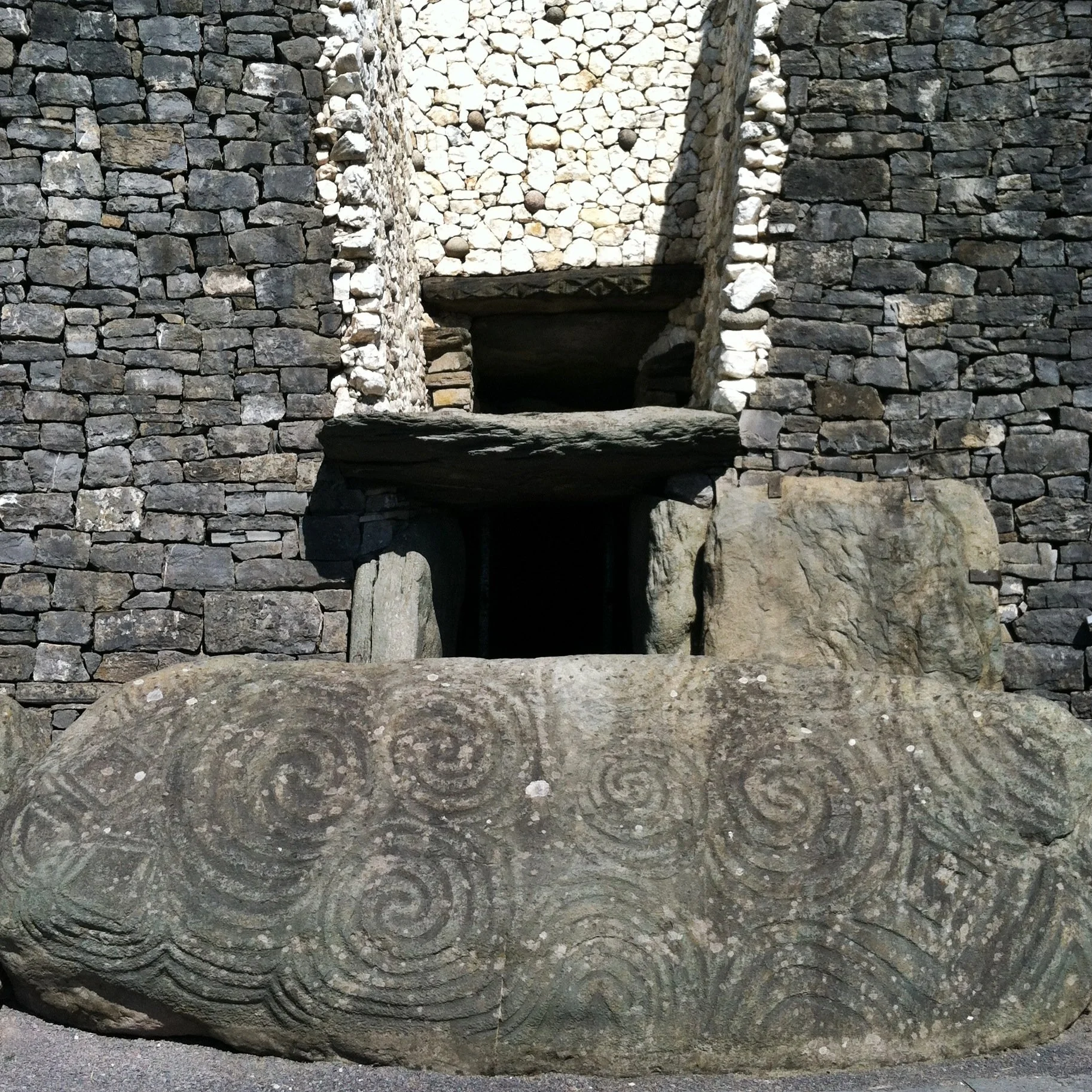 Close-up of a carved stone with spiral patterns, part of an ancient stone structure.