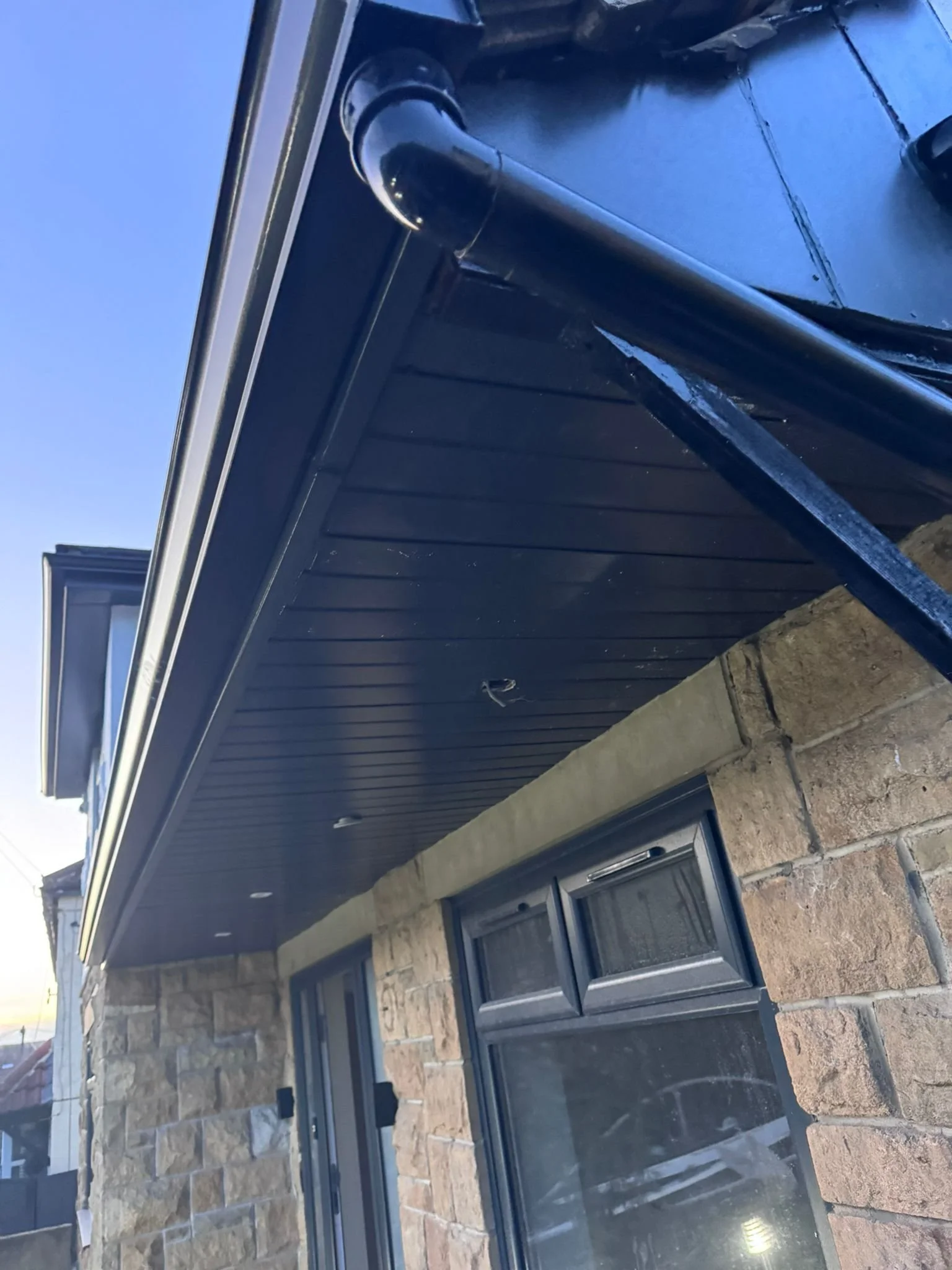 Close-up of a black glass door with a metal handle on a beige brick wall house exterior.