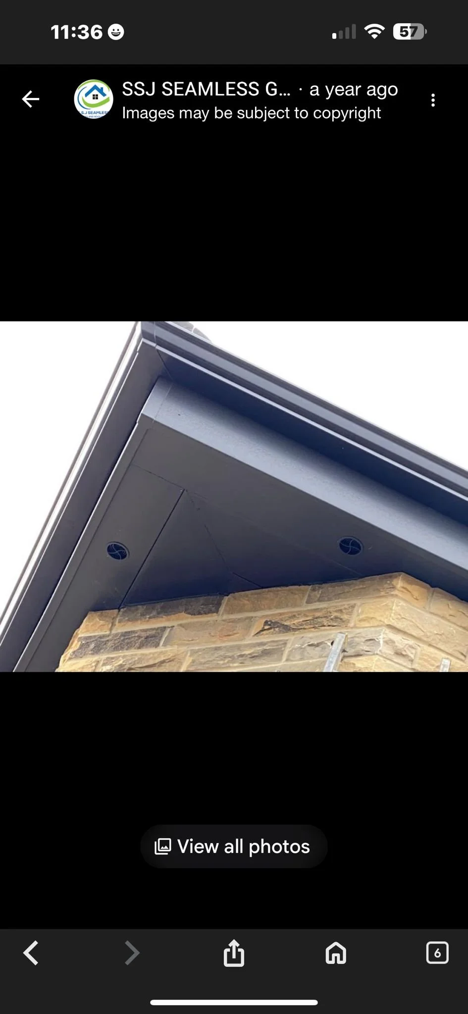 Close-up of a house's roof corner showing the eaves, soffit, and a section of a brick wall, with visible round vent holes.