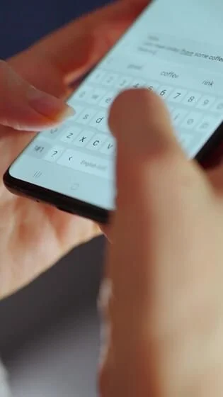 Close-up of a person typing on a smartphone with a calculator app open, showing numbers and mathematical symbols.