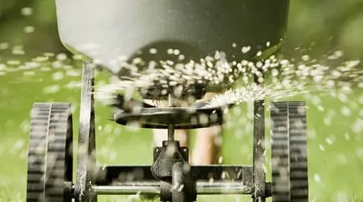 Close-up of a lawn sprinkler spraying water over green grass.