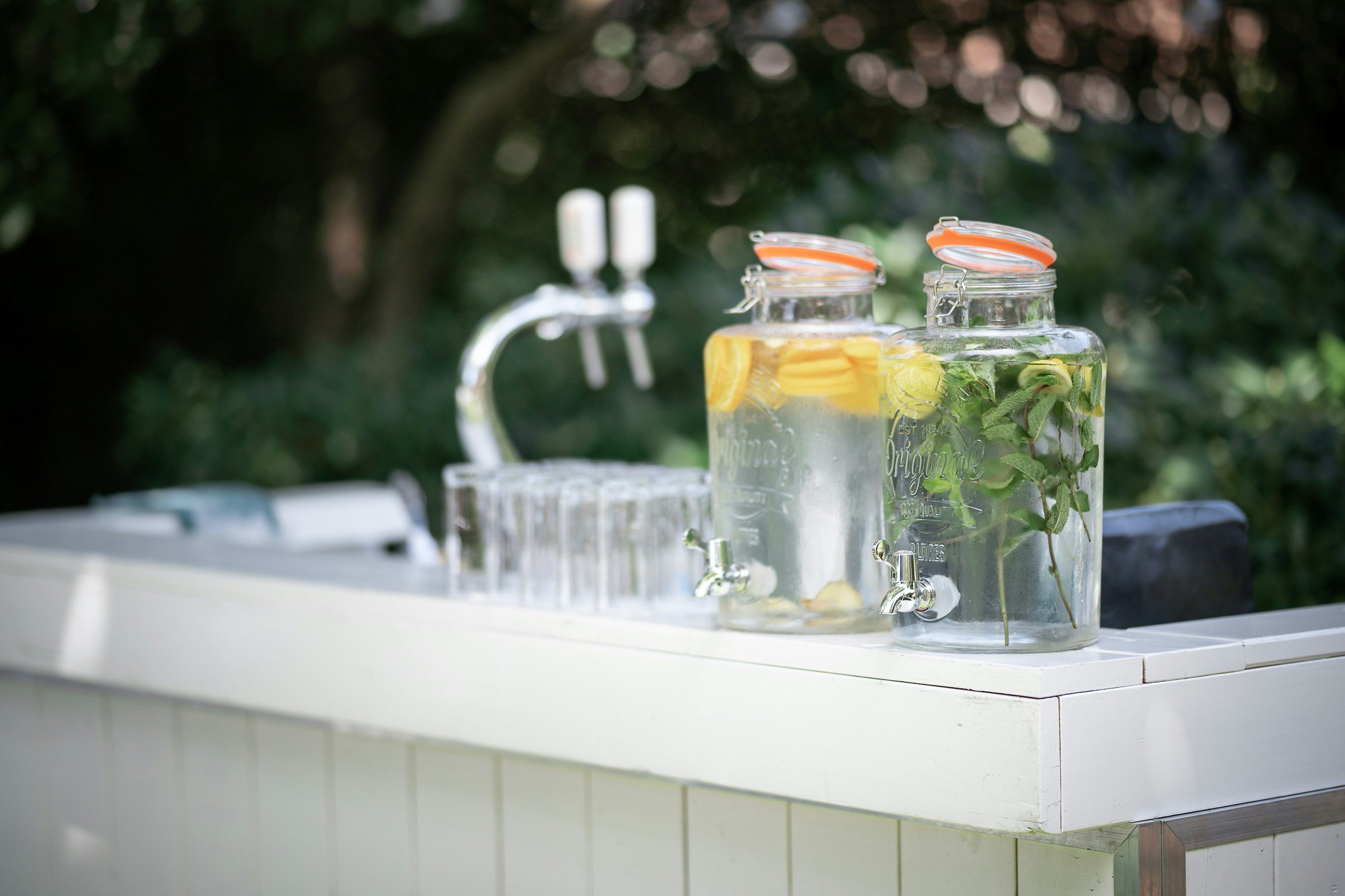 Deux jars d'eau infusée au citron et à la menthe sur un comptoir blanc en extérieur.