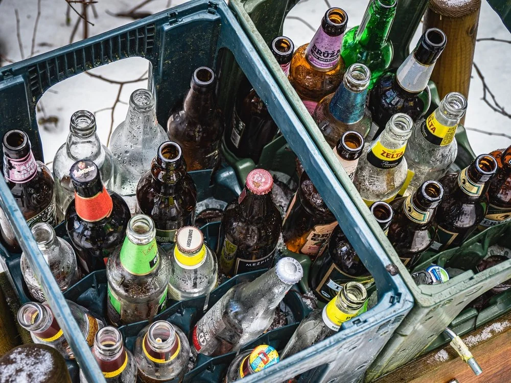 Bouteilles de bière dans des caisses en plastique, avec de la neige sur le sol.