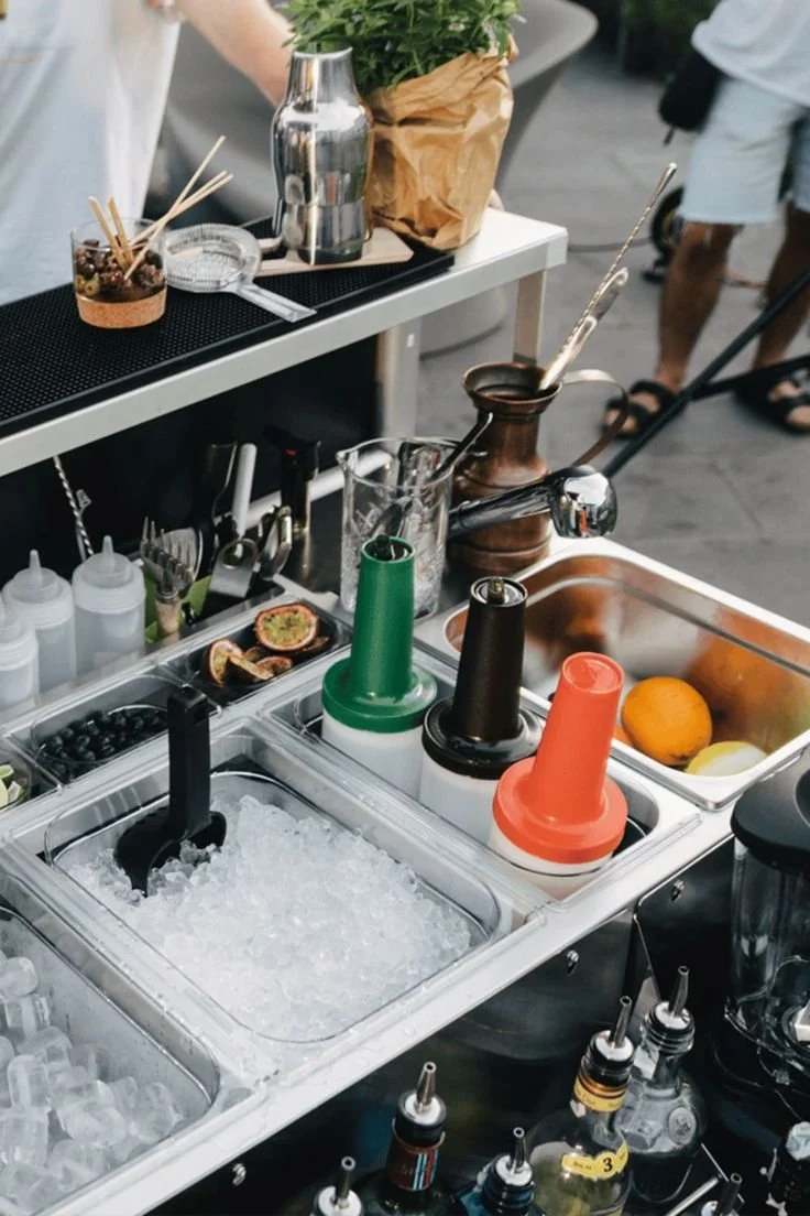 Bar à glacé avec plusieurs contenants de glace, sorbetière, fruits, et accessoires pour préparer des boissons ou des desserts glacés.