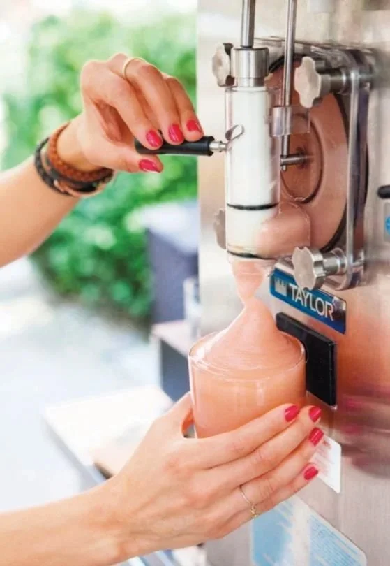 Une personne utilisant une machine à glaces pour faire une glace artisanale à partir de sorbet ou de glace mouillée dans un récipient en plastique.