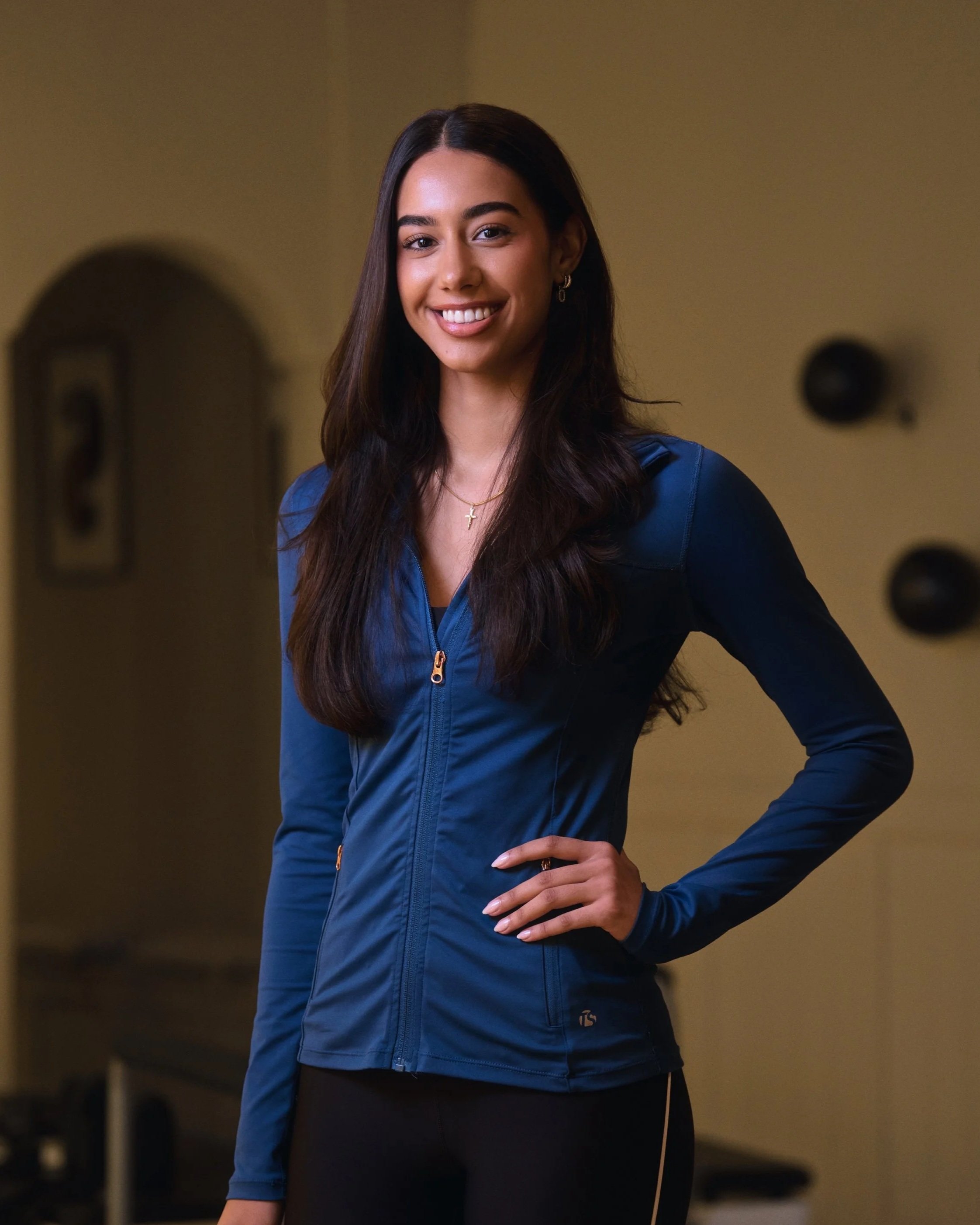 Pilates Instructrice bij Pilates Avenue in Leeuwarden, draagt een blauw sportvest in de moderne reformer pilates studio