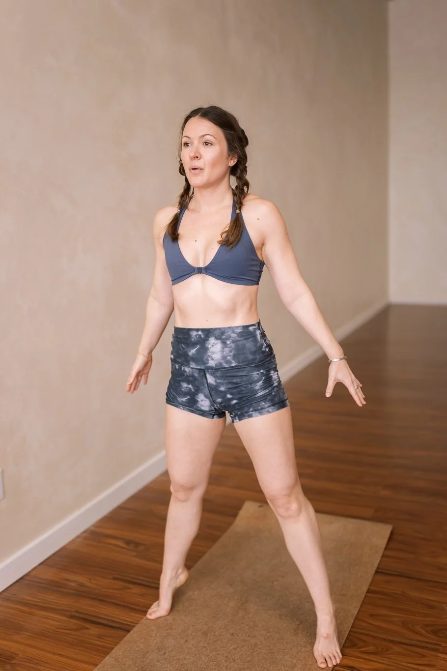 a woman doing yoga on a mat, wearing a sports bra and shorts, indoors