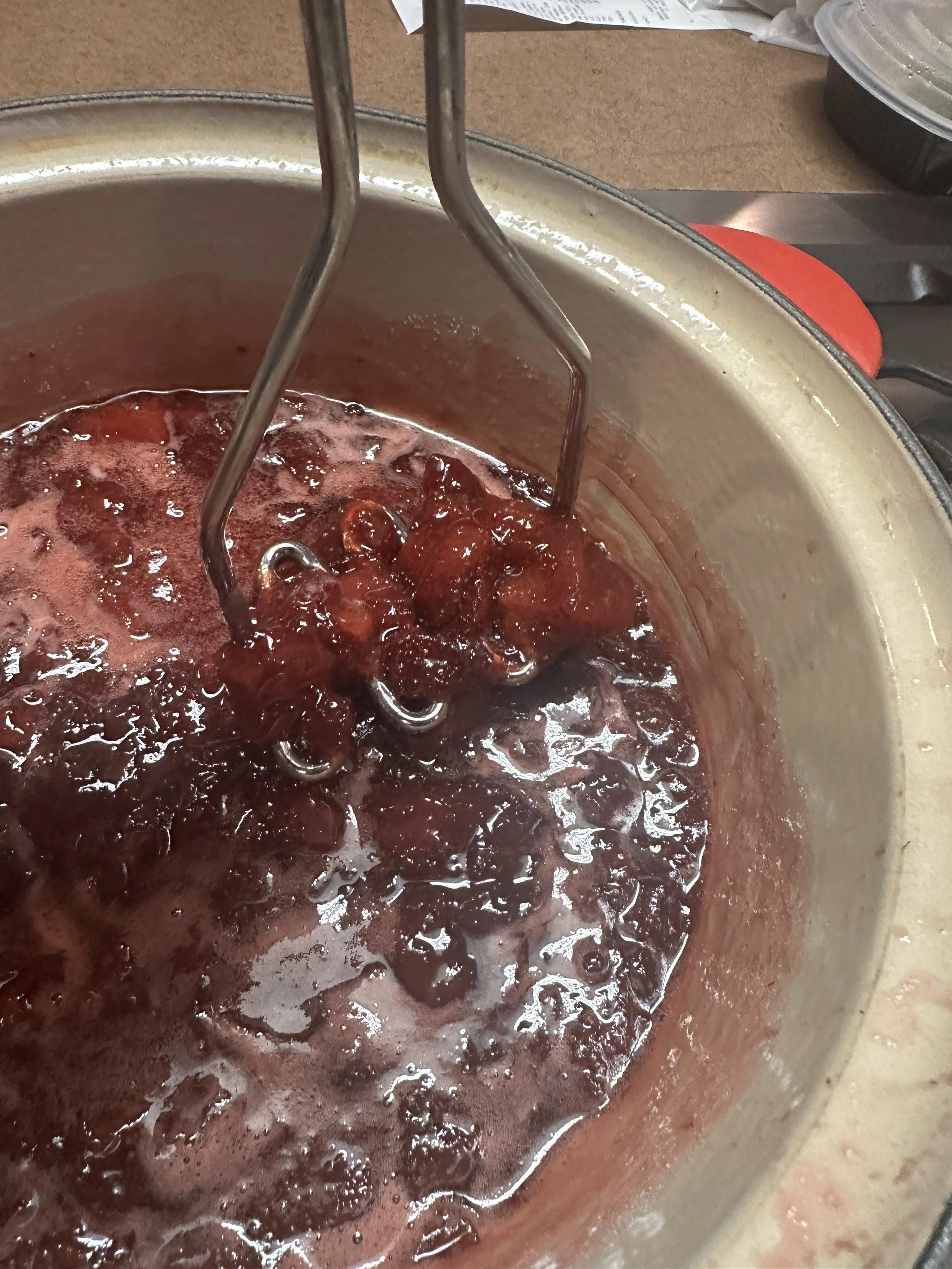 A pot with a cherry filling being heated, with a hand mixer attachment stirring it.