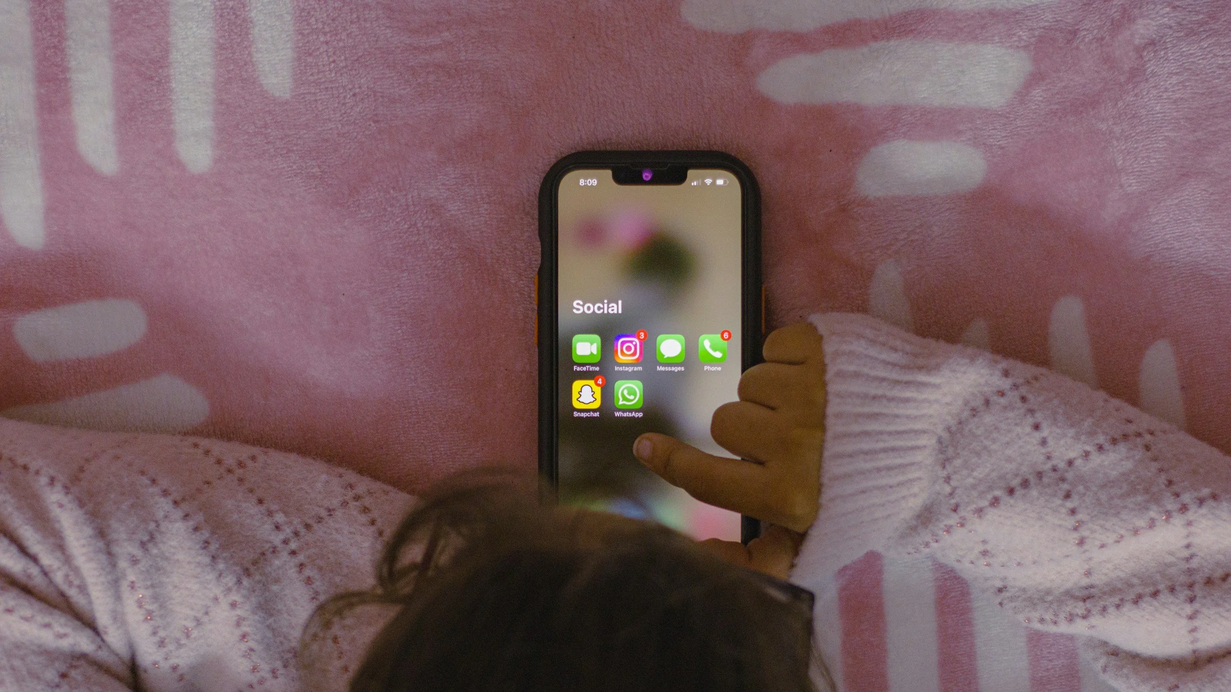 A mom looks social media apps on her phone while lying in bed - postpartum doula in Renton, Maple Valley, Issaquah, Bellevue, Newcastle