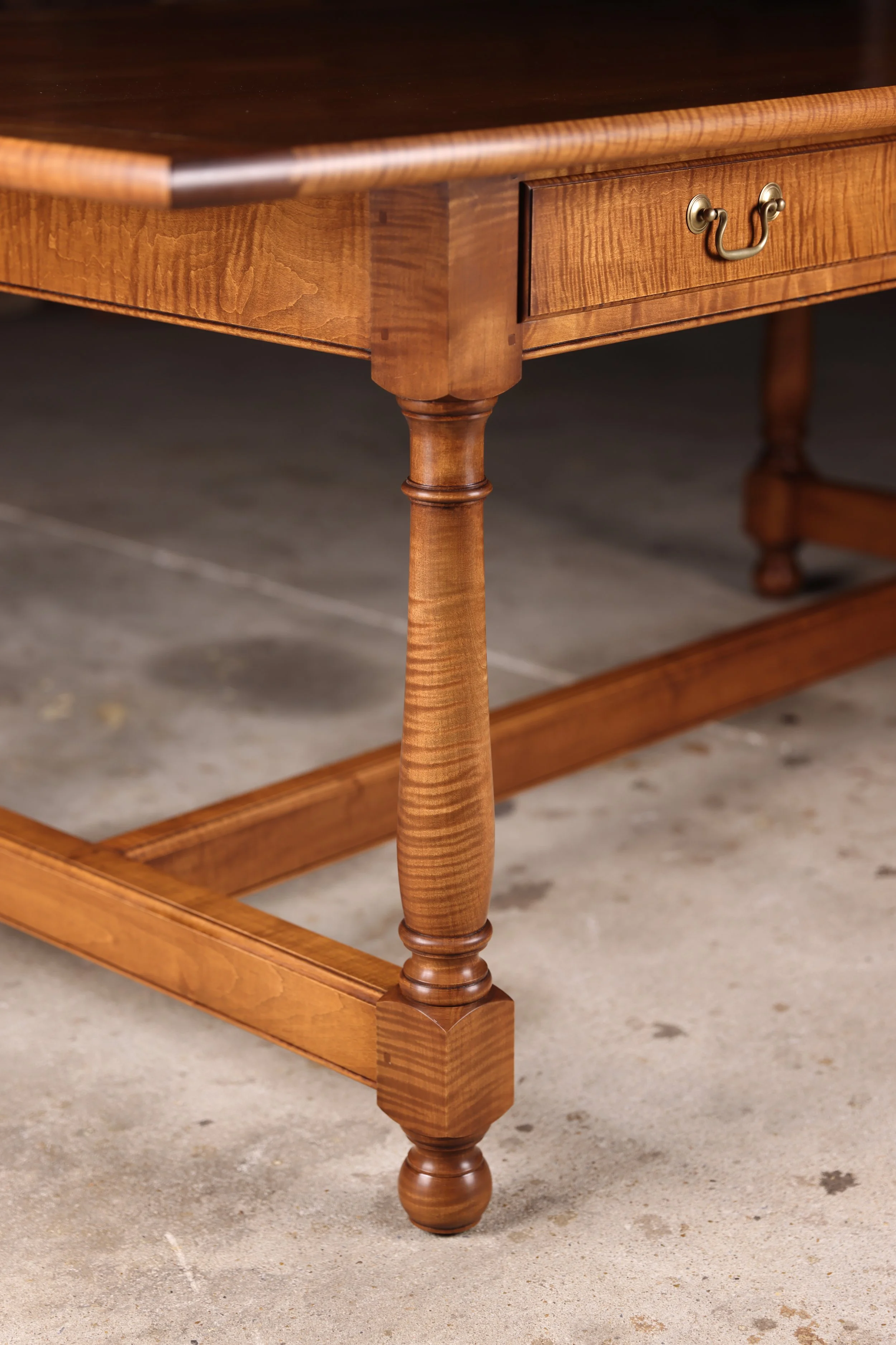Handcrafted tiger maple dining room table close up showing hand turned leg from solid three inch thick tiger maple.