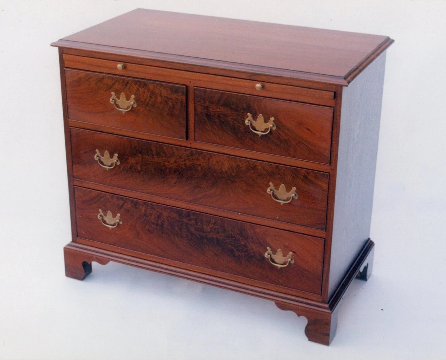 Handmade low chest with writing surface/brushing slide in walnut and crotch walnut.