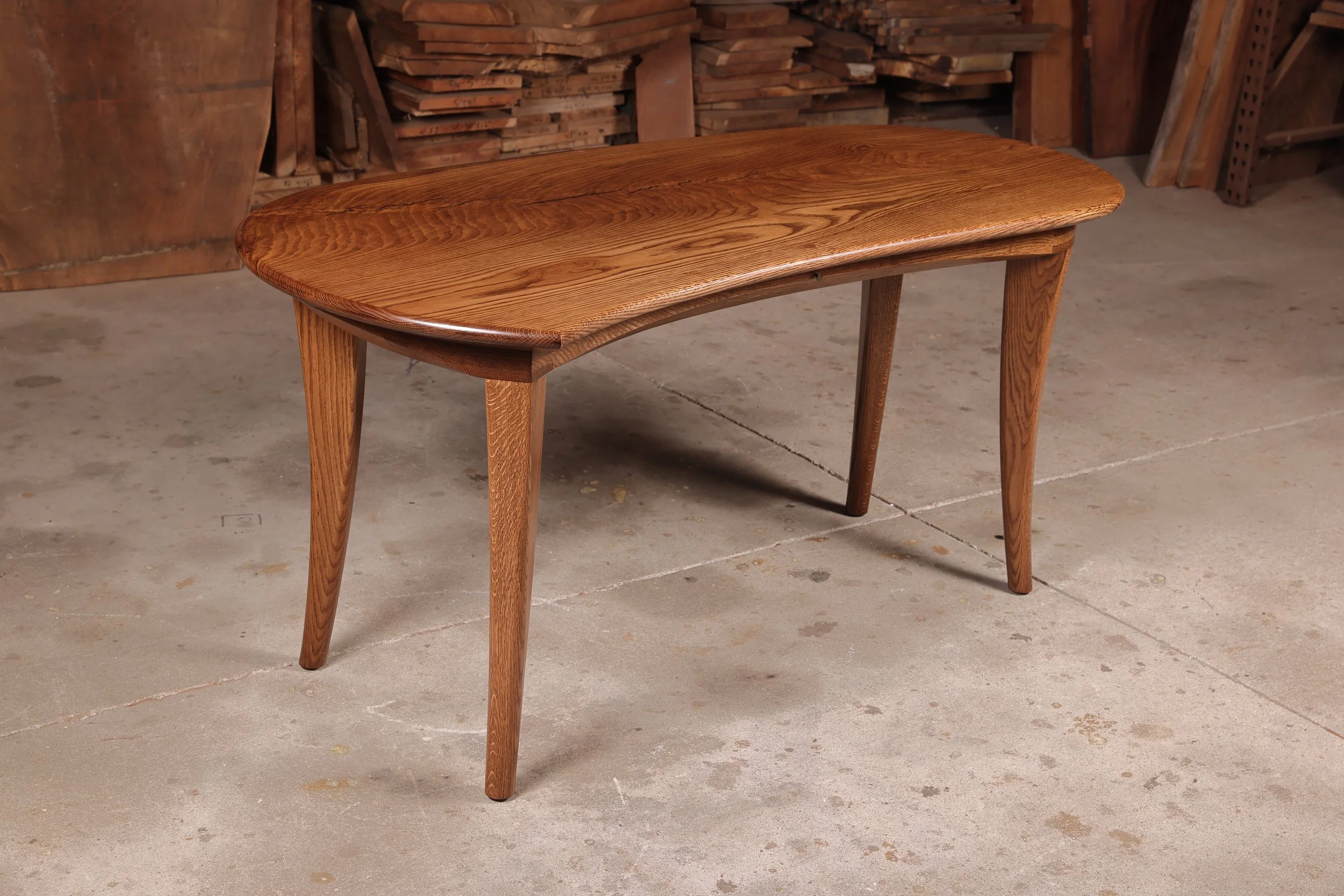 A custom made white oak writing desk showcasing a fluid, kidney-shaped top and sculptural tapered legs inspired by Wharton Esherick.