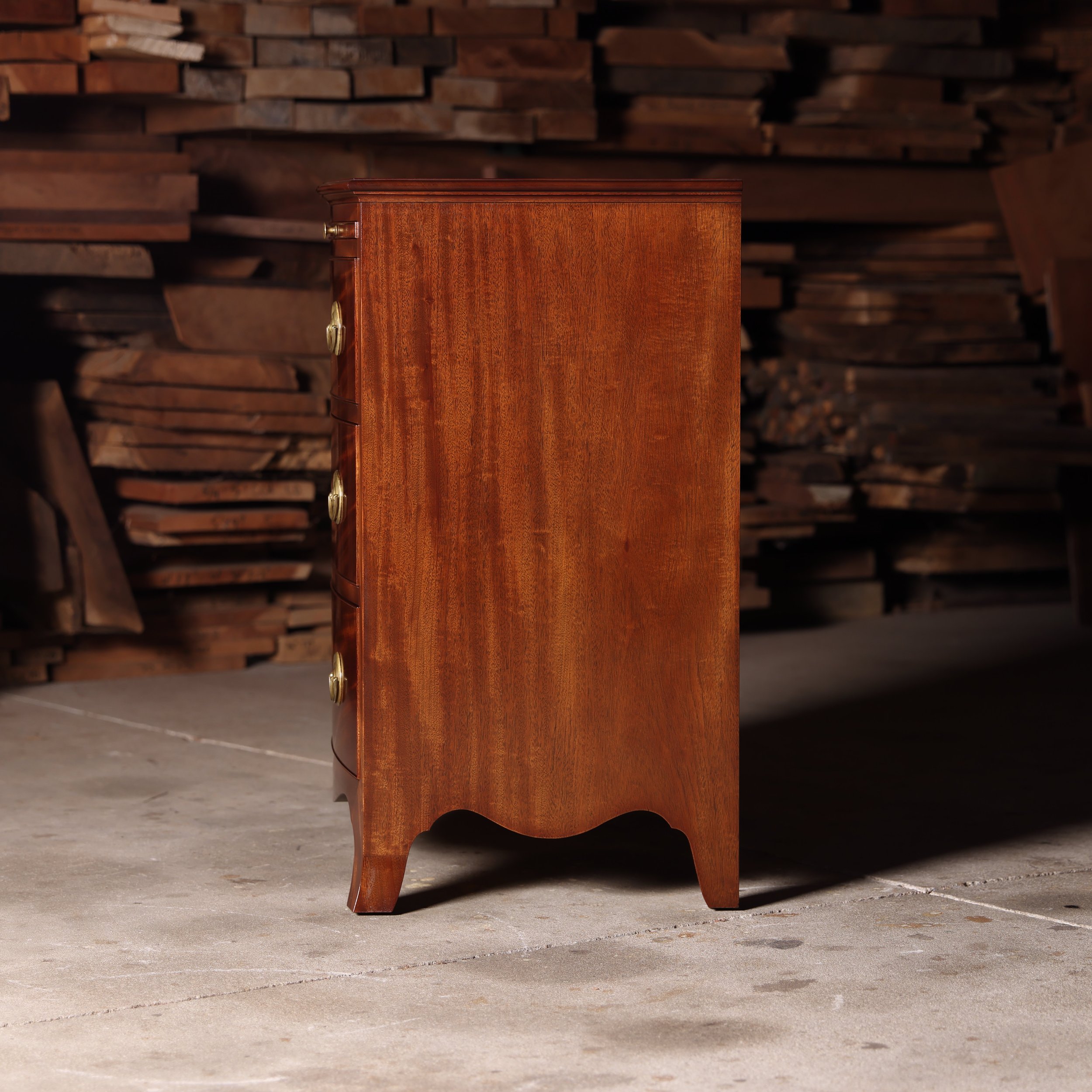 Handcrafted  bow front chest, left side view. Single wide mahogany case side.